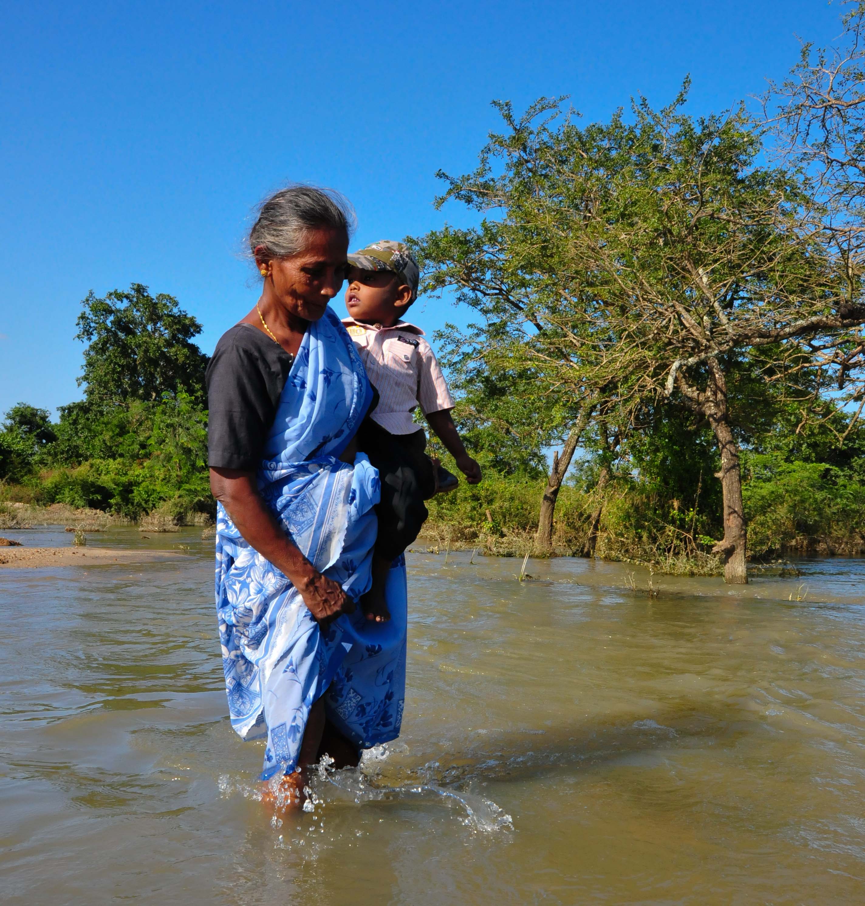 An old woman carries a child across flood waters in Sri Lanka's eastern village of Verugal during flooding in mid-January. An old woman carries a child across flood waters in Sri Lanka's eastern village of Verugal during flooding in mid-January. More than 1 million people were affected and over 300,000 displaced