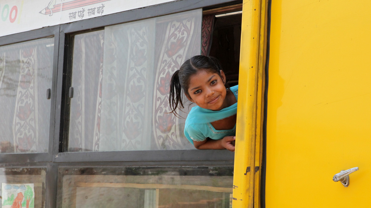 A child looks out of a window from a bus that serves as a school in India