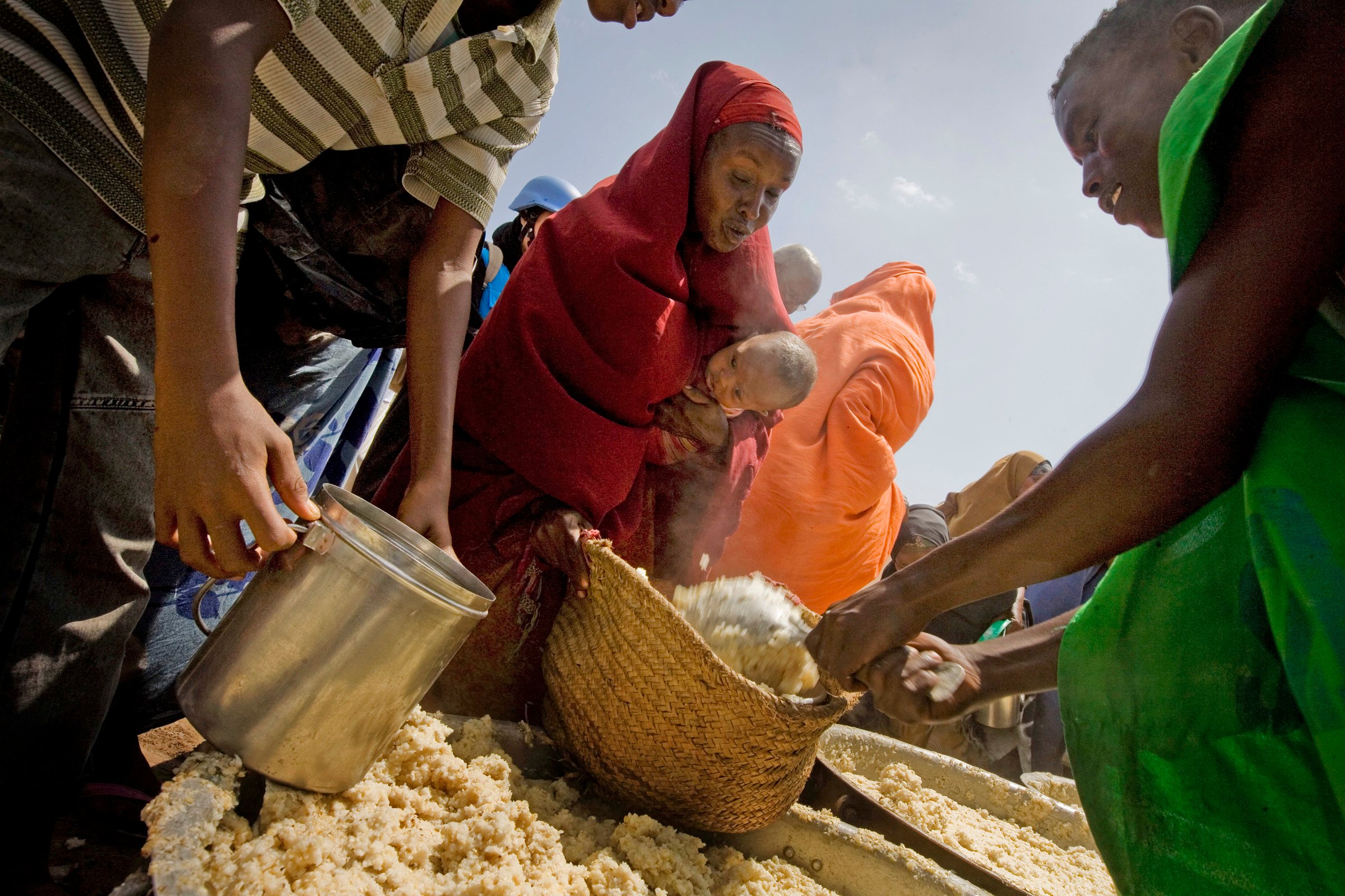 Women and children wait to receive a cooked meal at a food distribution organized by the WFP near the port in Mogadishu, Somalia