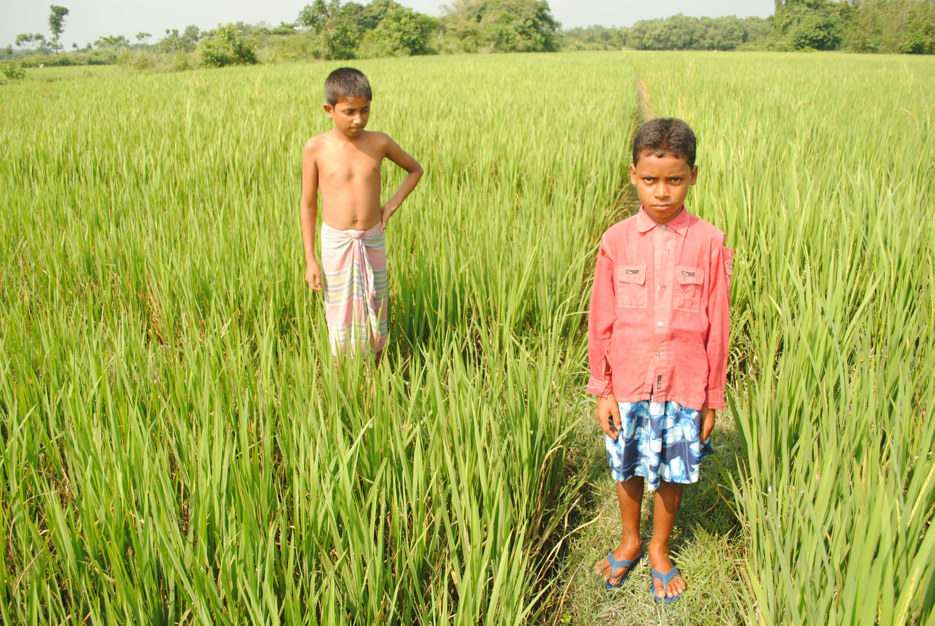 Bangladeshi brothers Anis Ahmed (L) and Shohir Jamal (R). Shohir is standing on the border between the two countries, with Bangladesh is to his right. Anis is on the Indian side