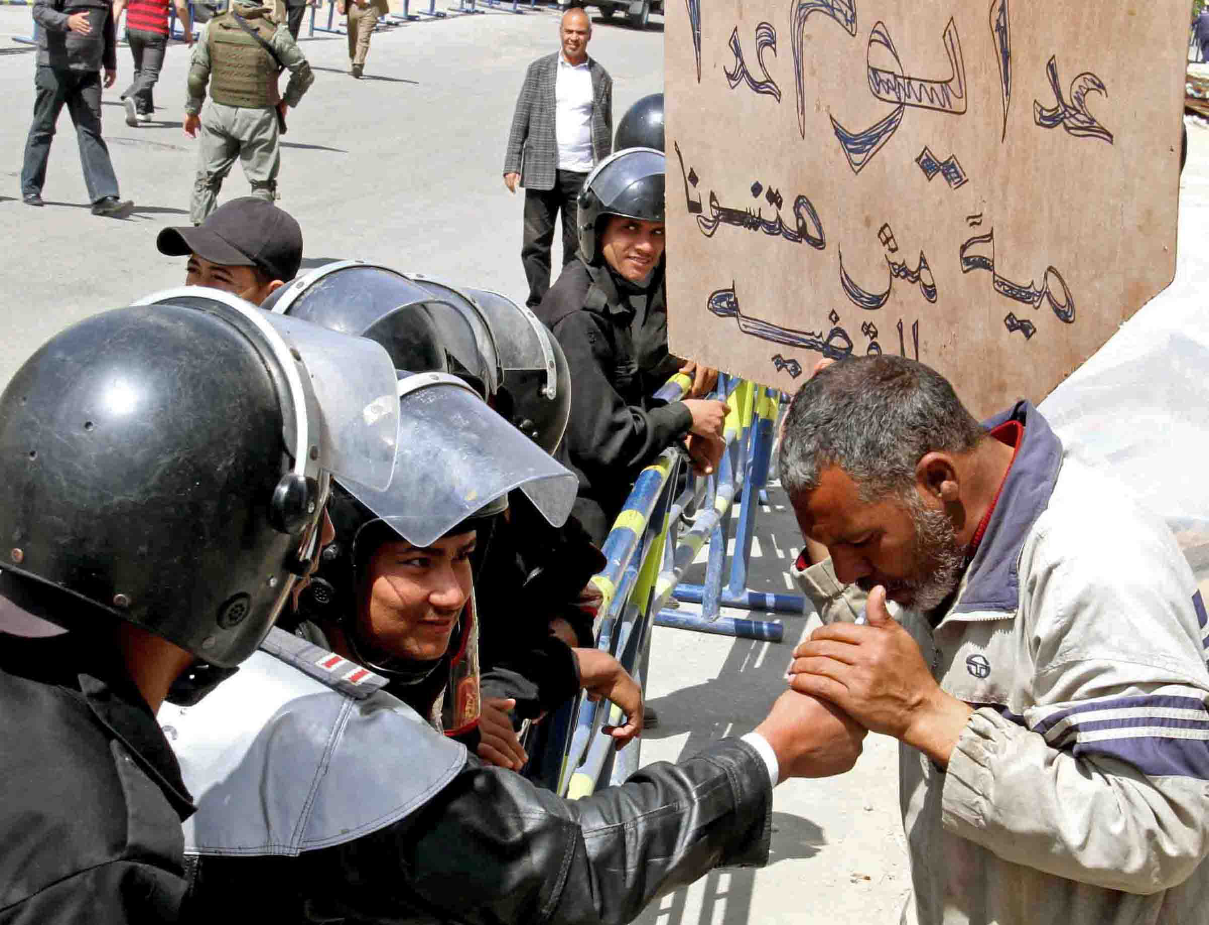 Activists in Cairo protesting against police brutality. One of them carries a placard that reads: "Your job is to protect us, not to torture us"