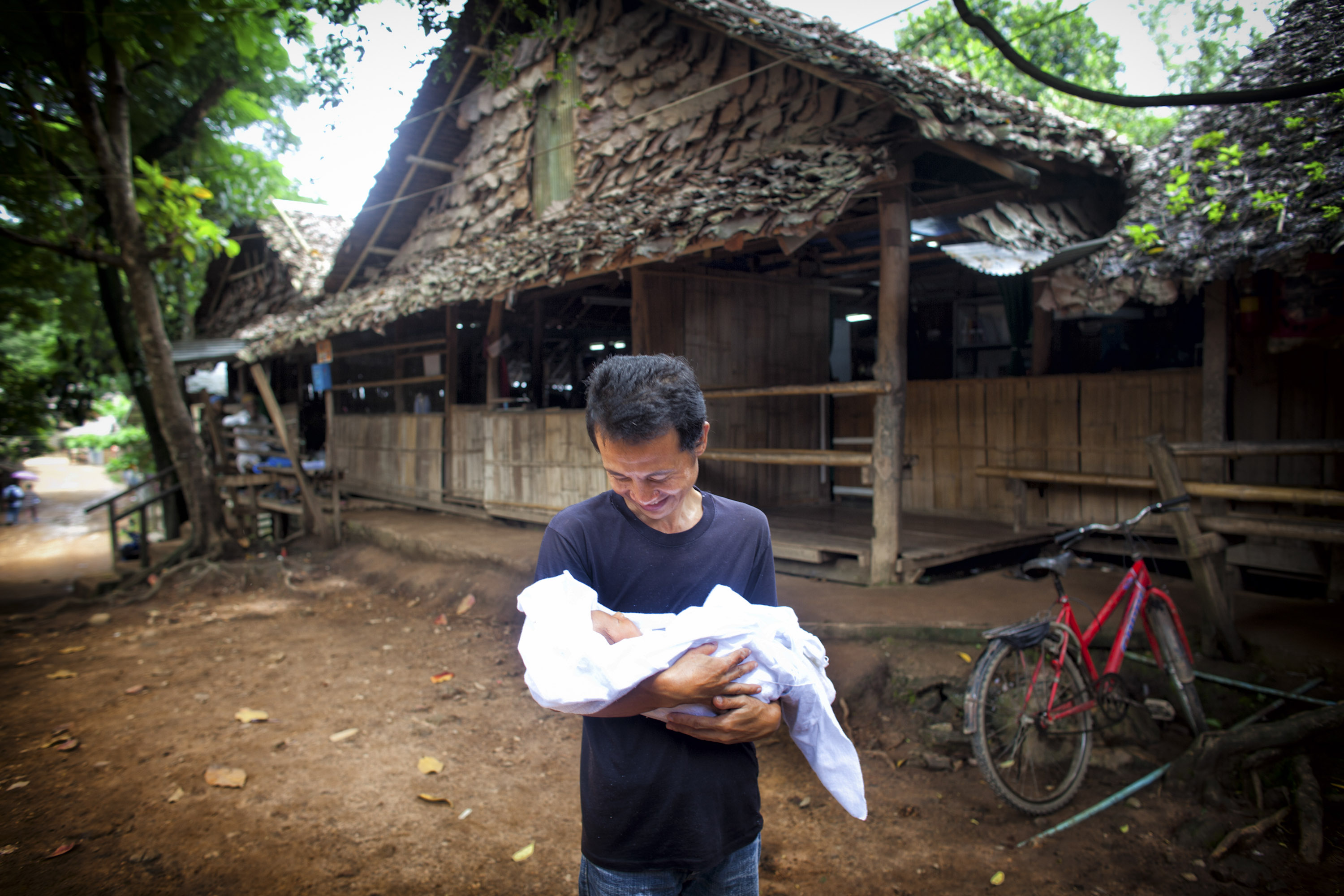 An ethnic Karen refugee father holds his new born infant at the Mae La refugee camp along the Thai-Burmese border