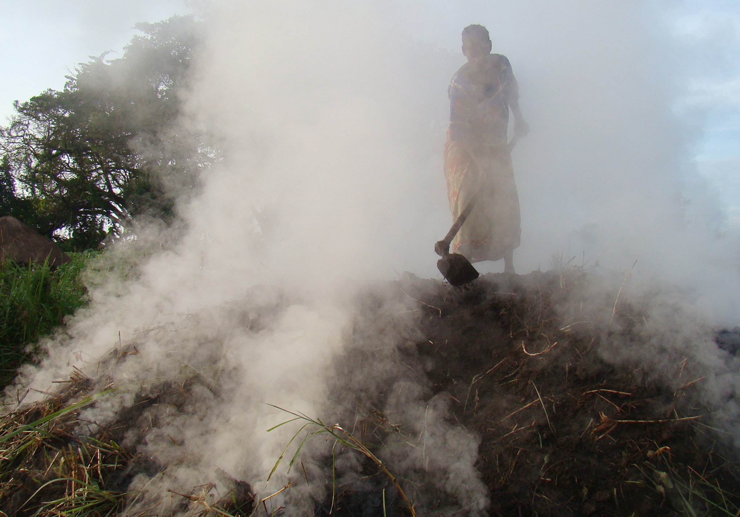 A woman on top covered with fuming smoke of burning charcoal in Nwoya
