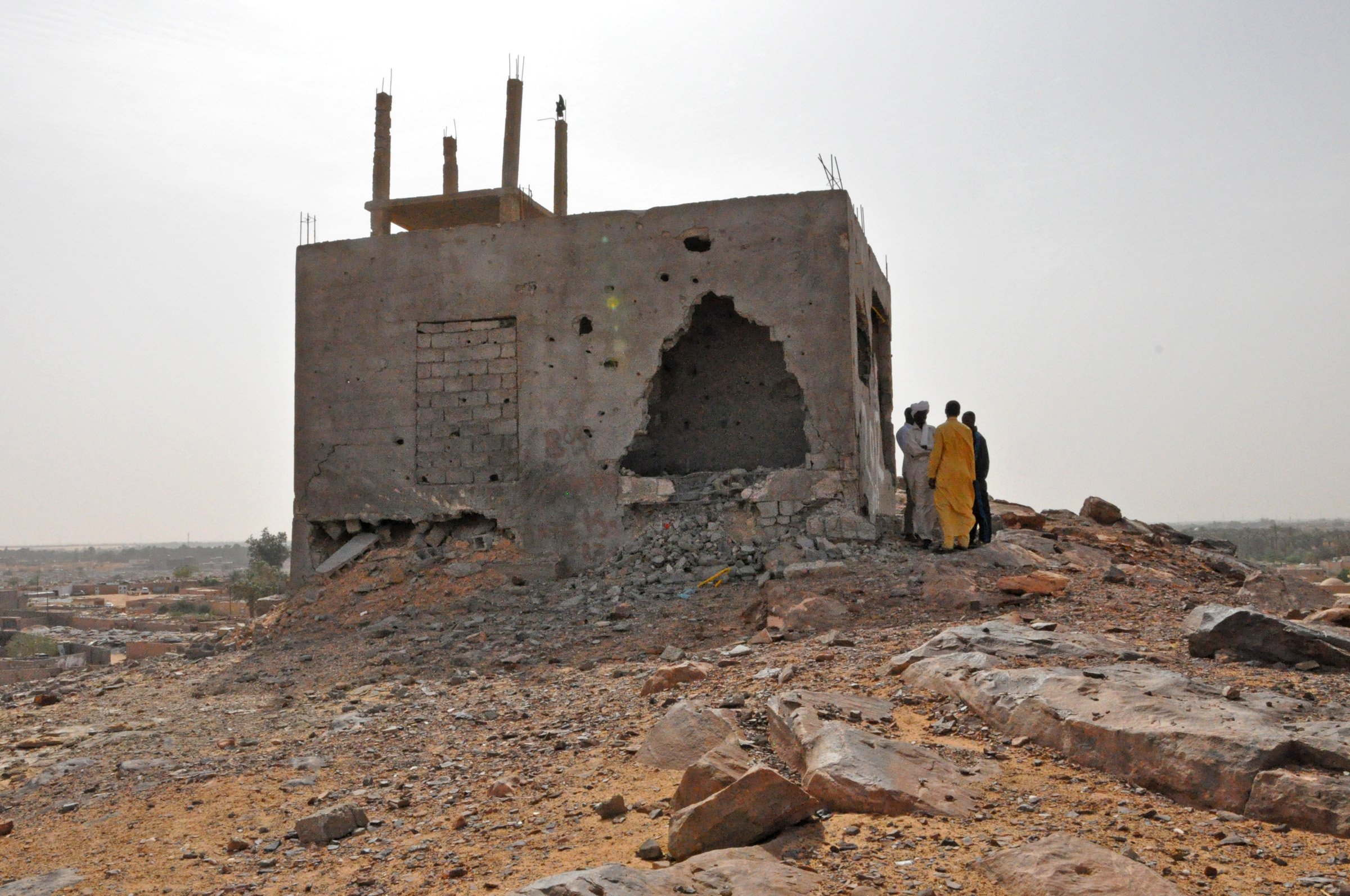 A group of Tubu from Tayuri stand outside the remains of an building which they said was used as a both a refuge and vantage point for shooting during the attacks