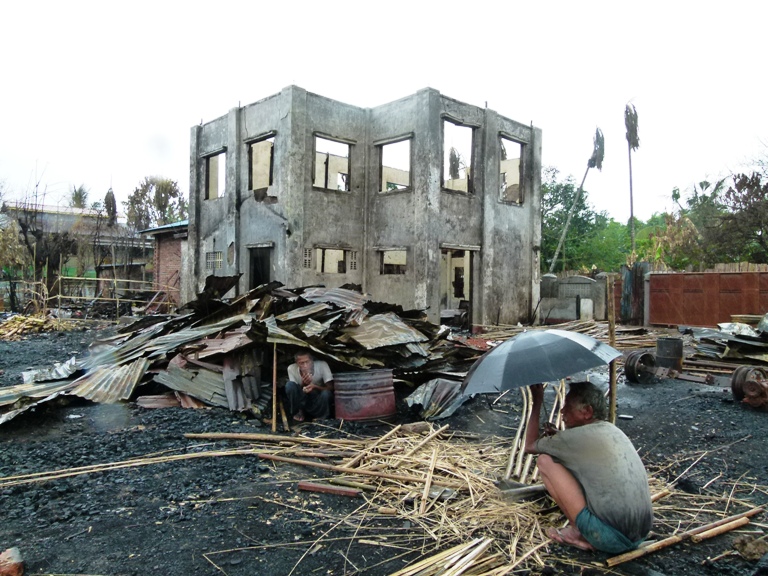 Two men sit under the the remnants of their homes in Sittwe, the provincial capital of Myanmar's western Rakhine State. More than 2,000 homes were destroyed in June following communal violence in the area