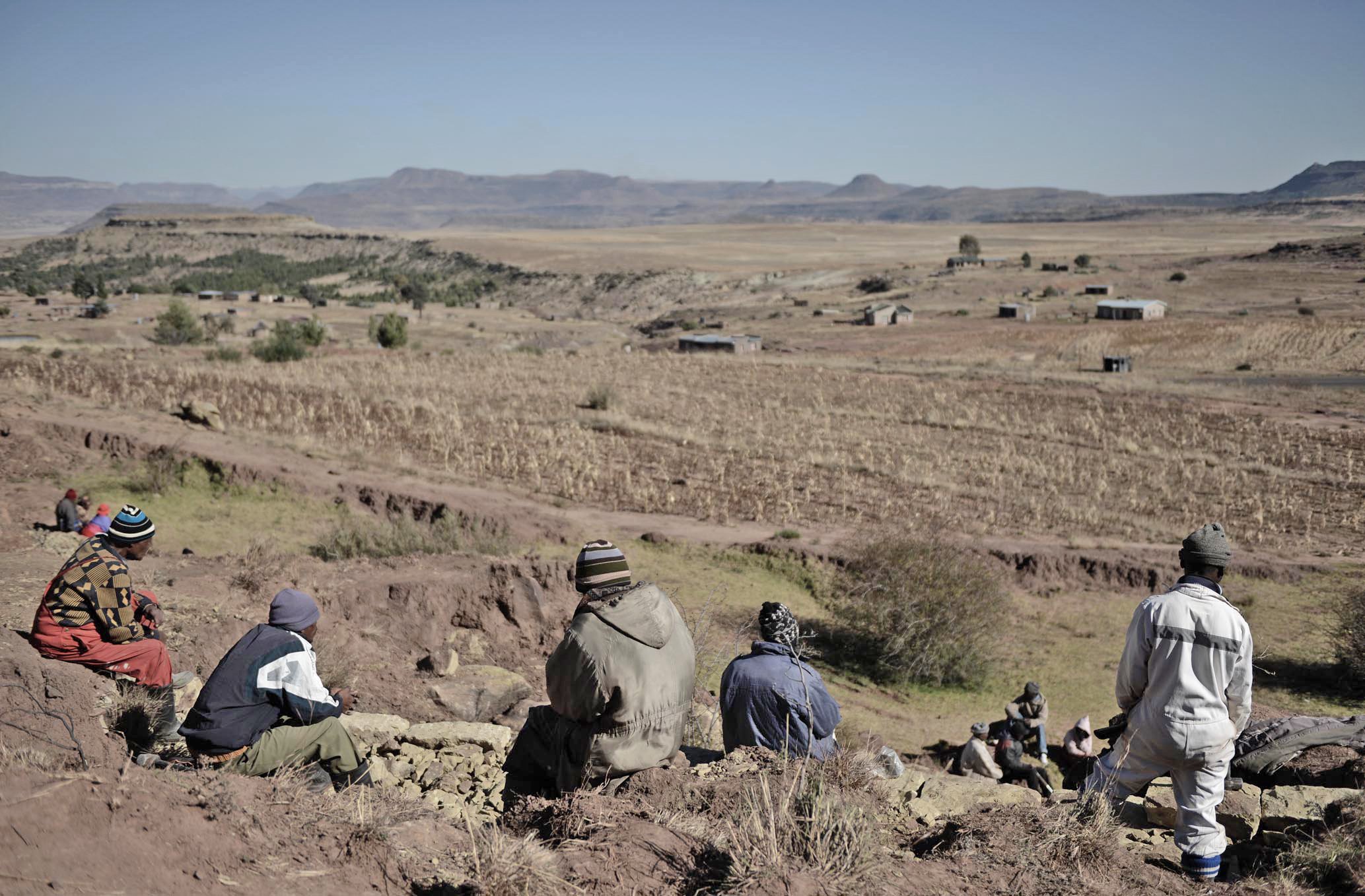 Members of a community from Lesotho’s south-eastern Mohale’s Hoek district take a break from work shoring up donga (ravine) to survey fields of failed maize caused by drought and then flooding