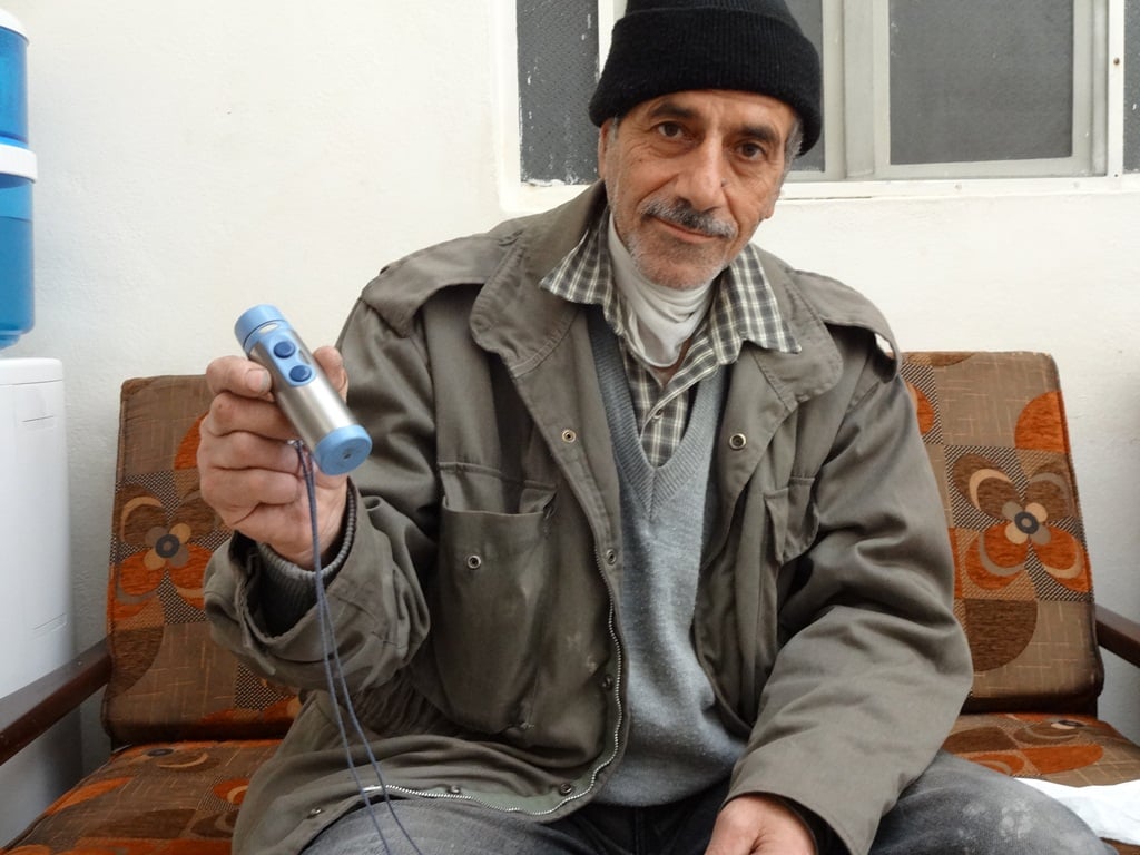 Eid Hanani uses this machine to help him speak after removing a cancerous tumour from his throat four years ago. Now, he has discovered a new cancer in his bladder, and the injections he needs for treatment are no longer available in Syria because of the 