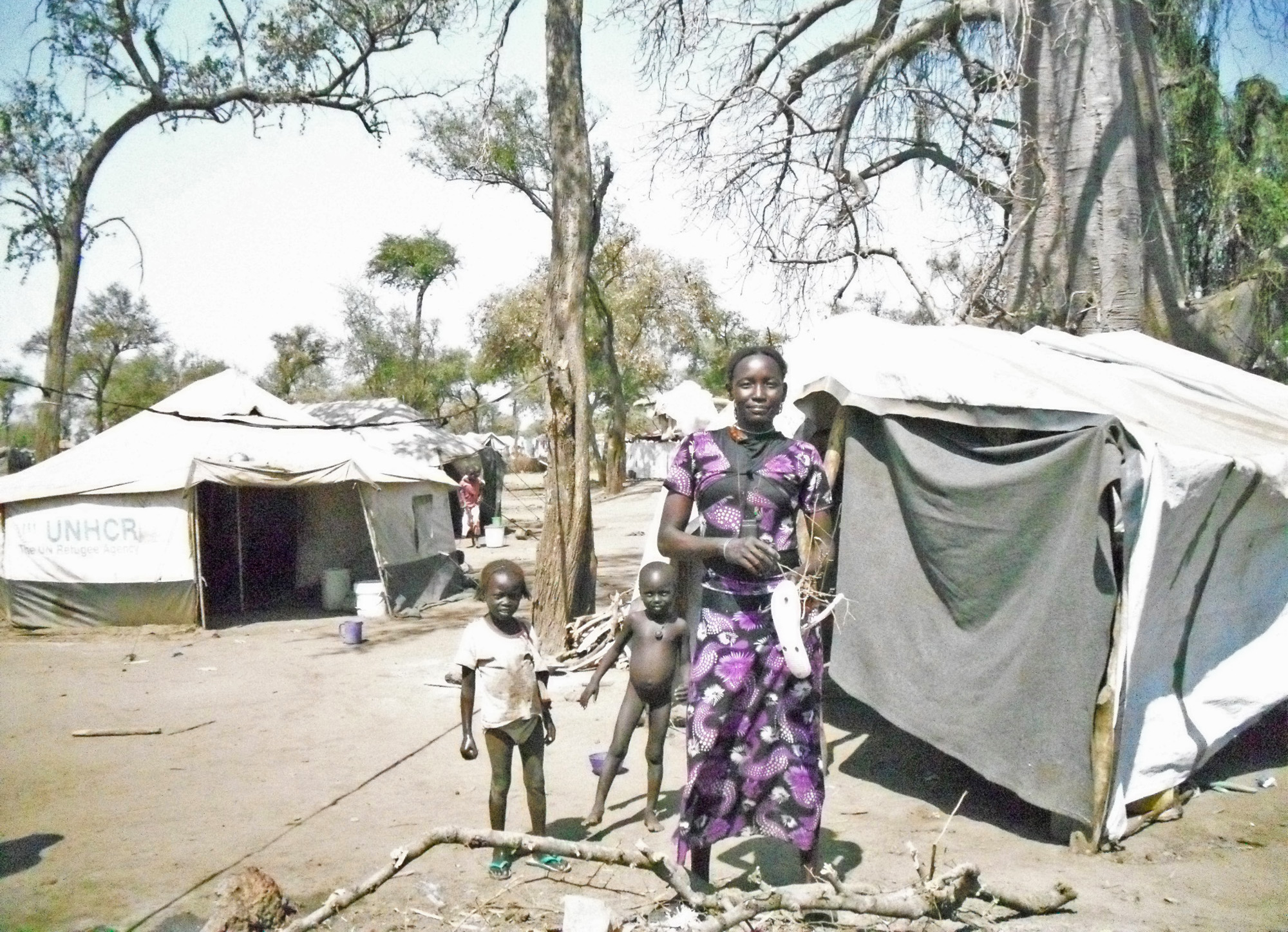 A woman with her children outside their home in Batil camp