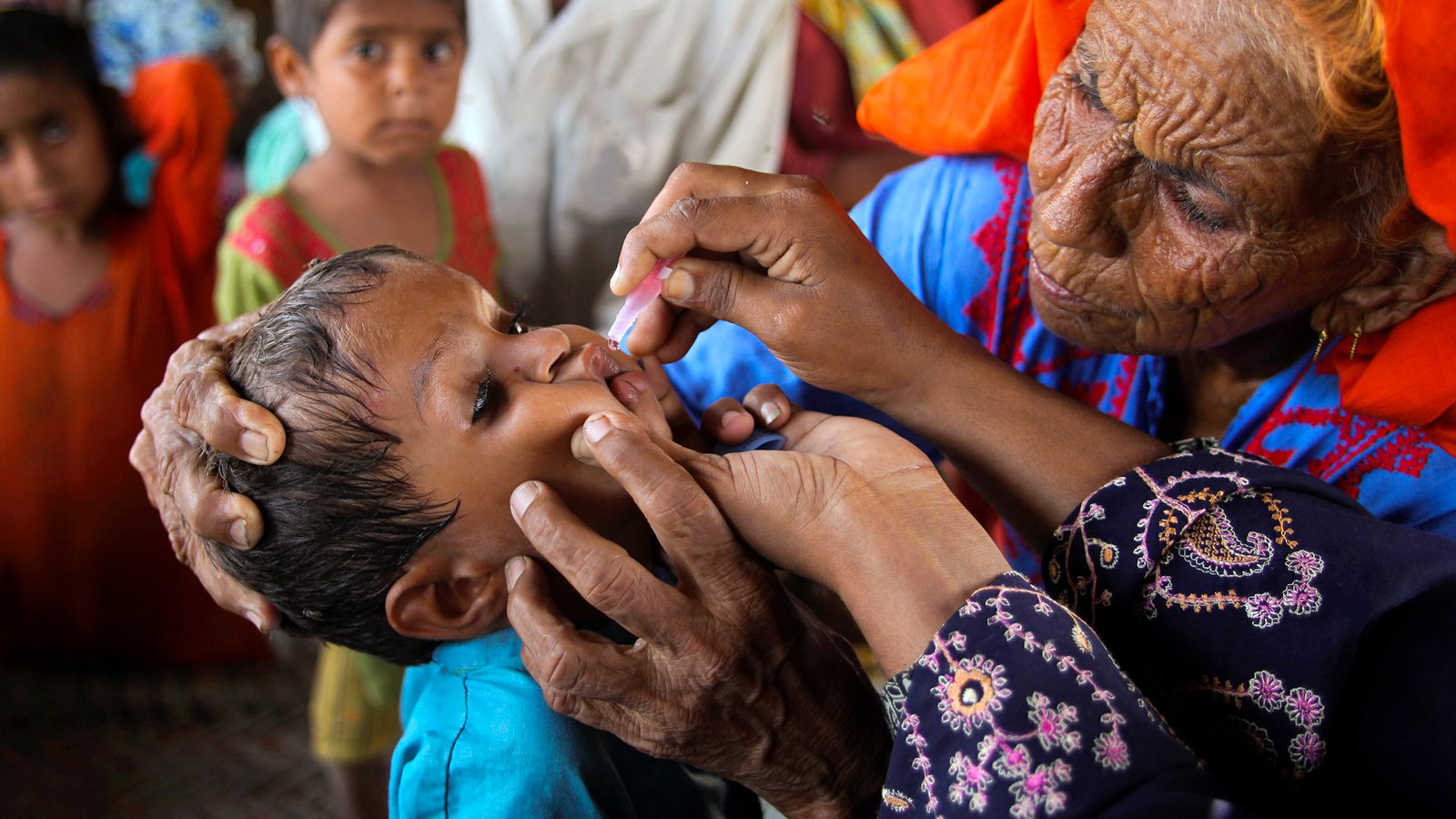 A lady health worker vaccinates a child against polio in flood-affected Sain Dad Katohar village in Khairpur district, Sindh province