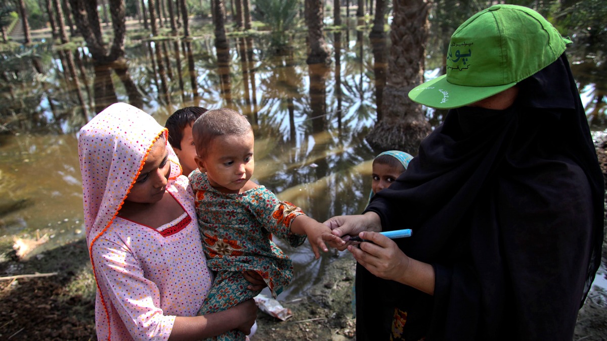 A Lady Health Worker (LHW) marks the finger of a child after administering the polio vaccine in flood-affected Bhano Goth village in Khairpur district, Sindh province