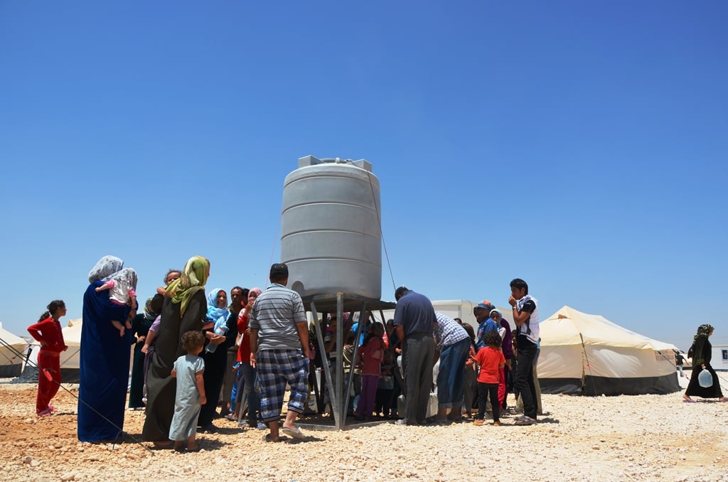 Syrian refugees line up for water at Za'atari Camp in northern Jordan. UNICEF trucks in 3.5 million liters of water a day to the camp, yet refugees say it runs out within minutes of arriving at the tank