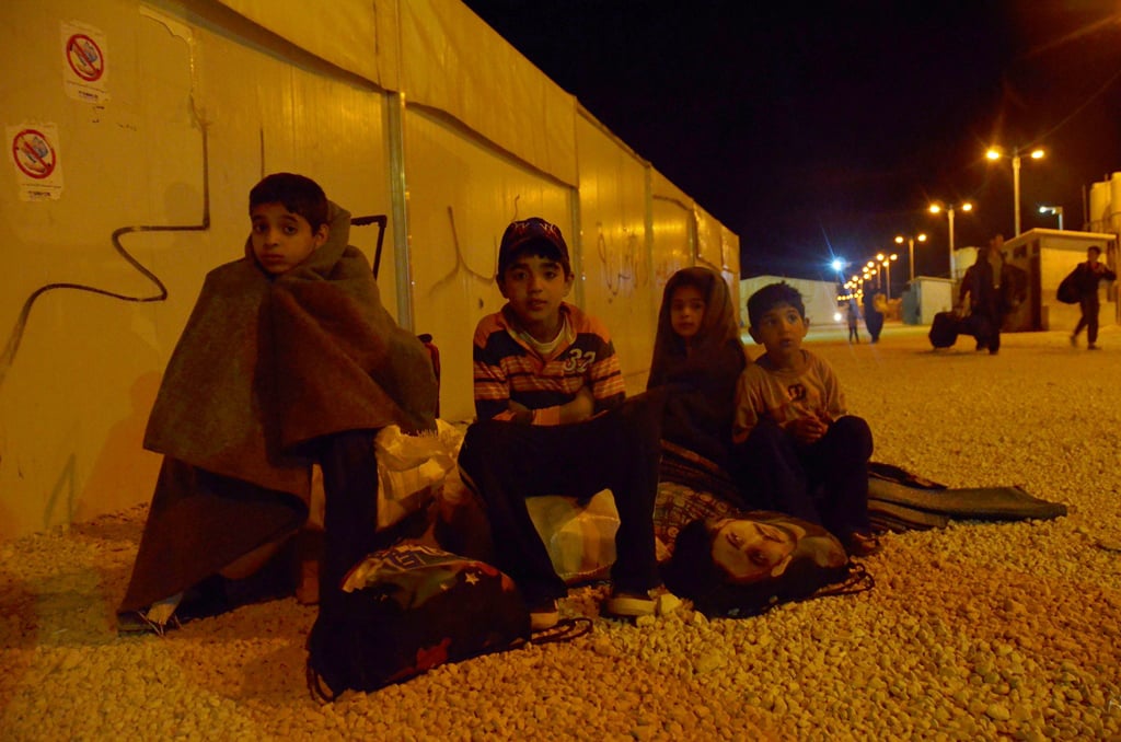 Children wait in the cold as their parents register as Syrian refugees in Jordan's Za'atari camp. Most attempt the illegal border crossing at night, when they believe it to be safer, arriving in Jordan in the middle of darkness