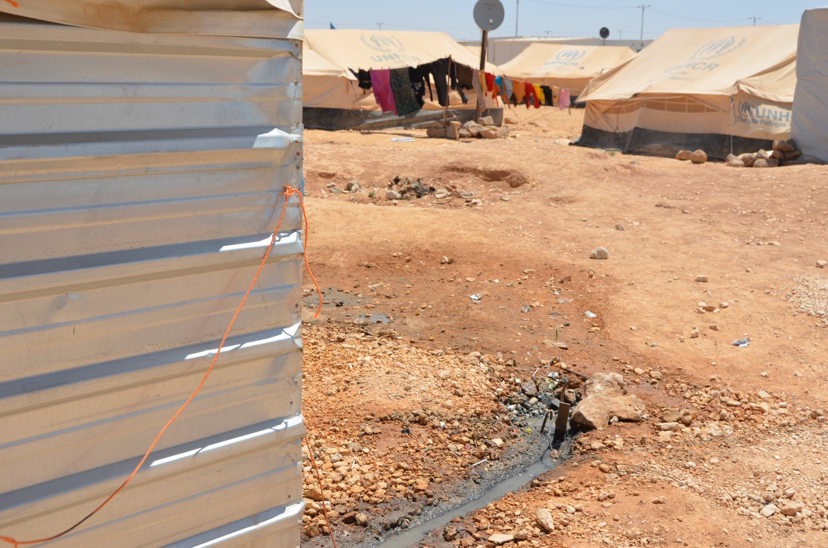 Dirty water seeps out of a make-shift washroom attached to a refugee's tent in Za'atari camp for Syrians, northern Jordan. These soak pits pose health risks and could pollute underground water aquifers. 