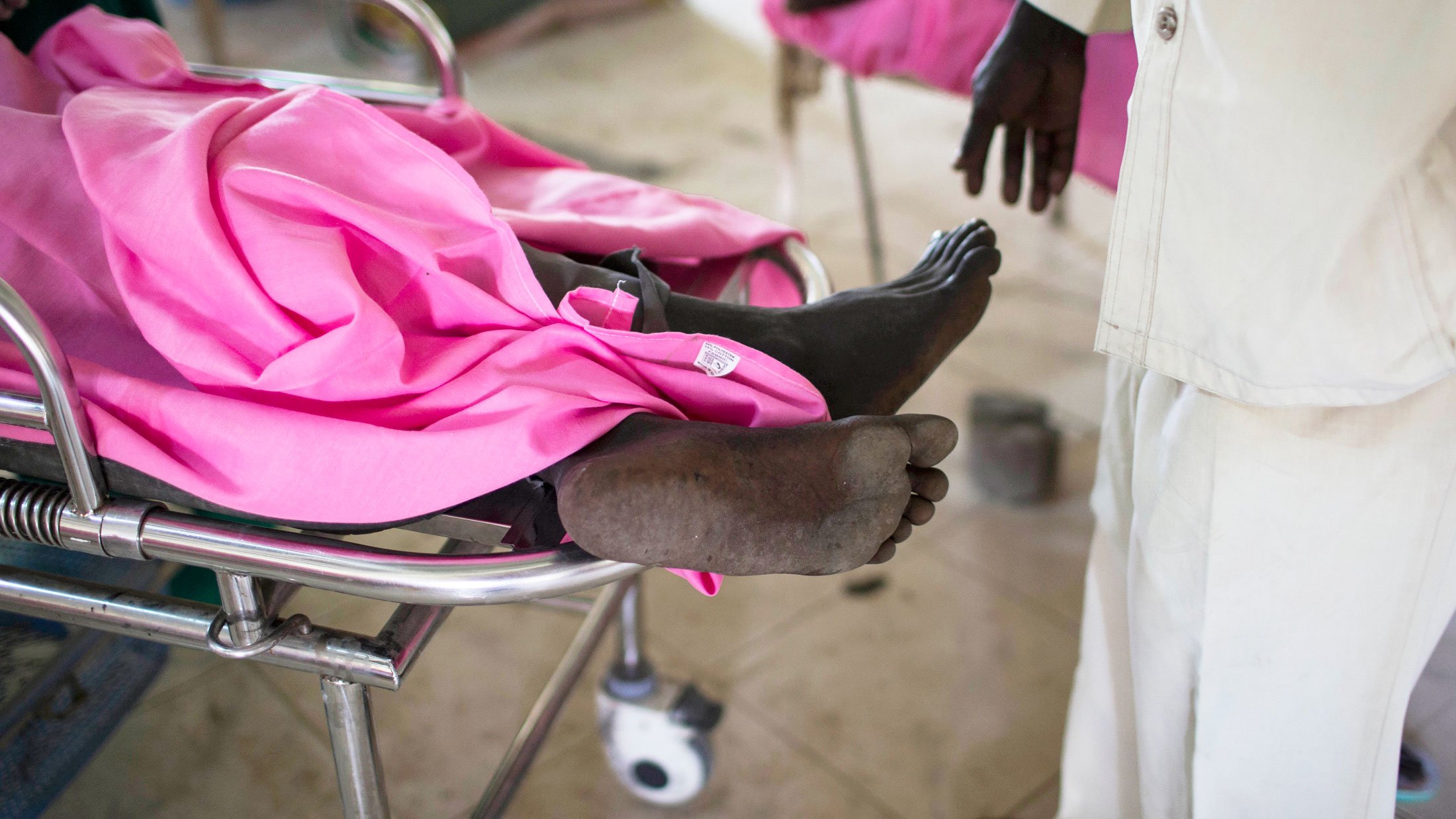 A man is wheeled into a recovery room at Bor hospital after undergoing an operation to mend a gunshot wound, Bor hospital, Bor town, Jonglei state, South Sudan, Monday, July 15, 2013. Fierce clashes between rival ethnic groups have again erupted in easter