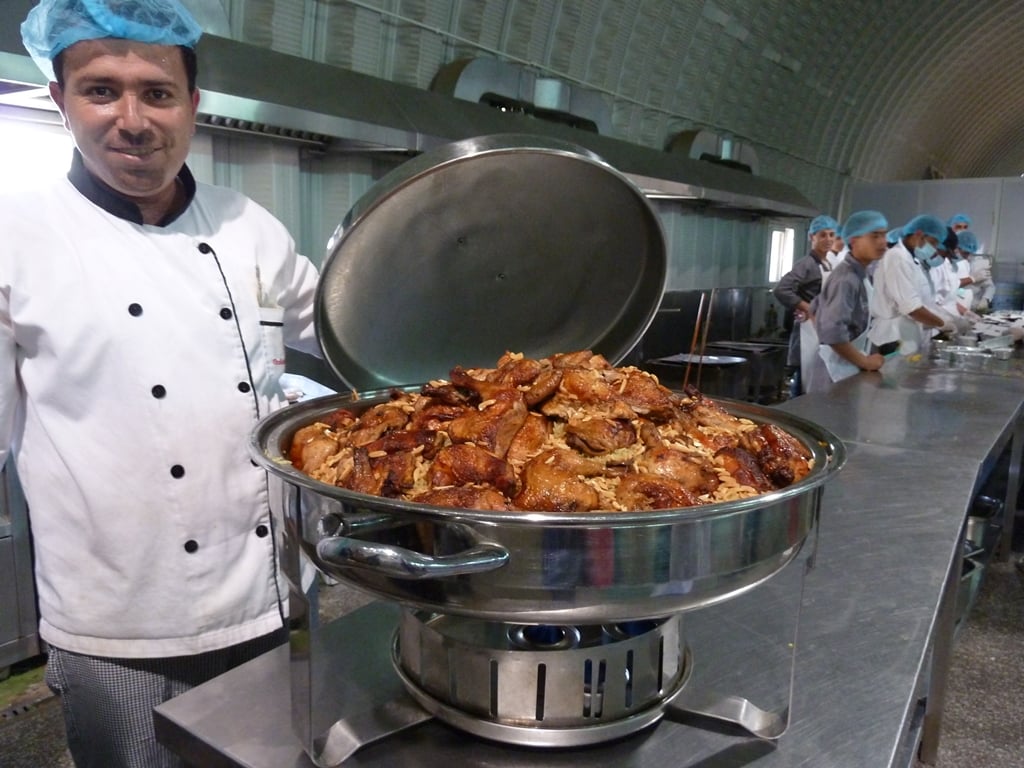 At the "five-star" camp for Syrian refugees in Jordan, run by the United Arab Emirates Red Crescent (UAERC), kitchen staff (in the background) pack rotisserie chicken, flavoured rice and grilled vegetables for refugees  in take-away boxes