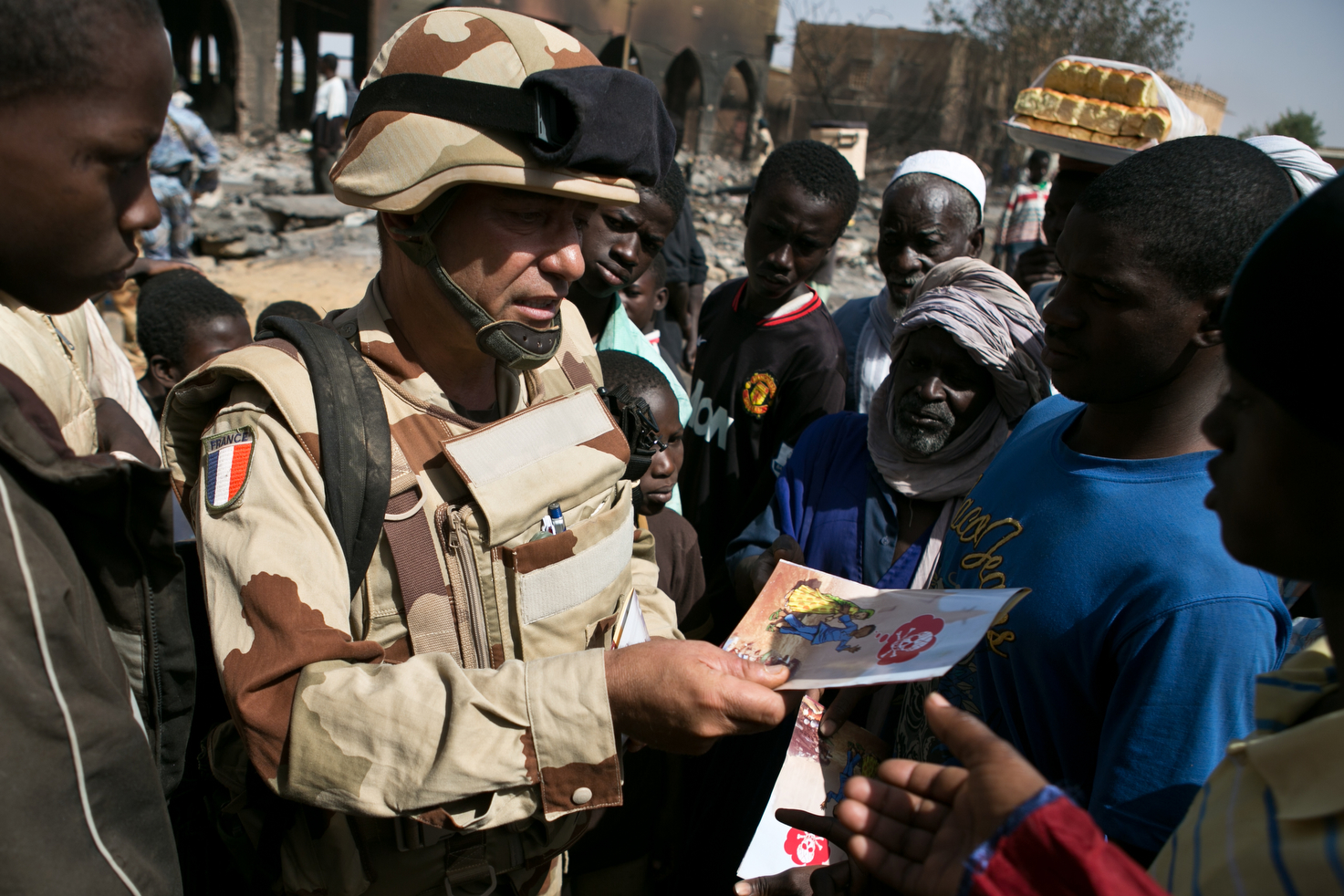 A French soldier passes out safety material on mines in the damaged market area of downtown Gao, after fighting between radical Islamist rebels and French and Malian forces left it in ruins in Gao, Mali, 2 March 2013.