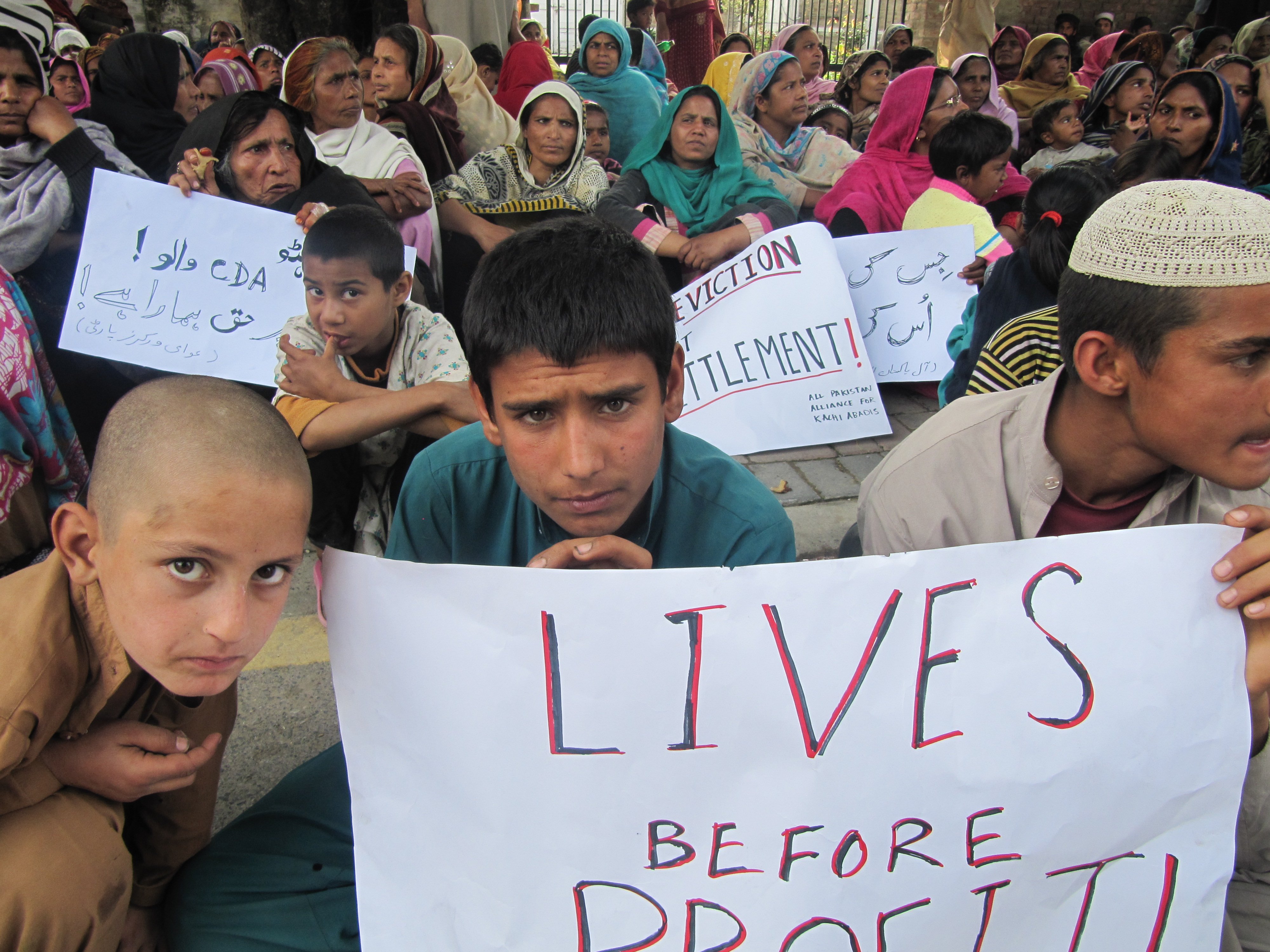 Ghaffar Ali, 14 (center) attends a protest against evictions of slums in Pakistan.  Ghaffar sells vegetables from a cart in the capital Islamabad's main produce market.  He says his family is from Bajaur Agency, but has lived in Afghan Basti, a nearby slu