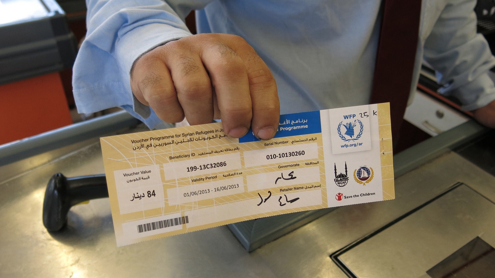 A shopkeeper holds up a WFP food voucher in a supermarket in Jordan