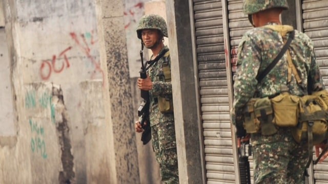 Marines soldiers patrol a community in Zamboanga City. One year after a deadly Muslim rebel siege on the city, the area remains insecure. 