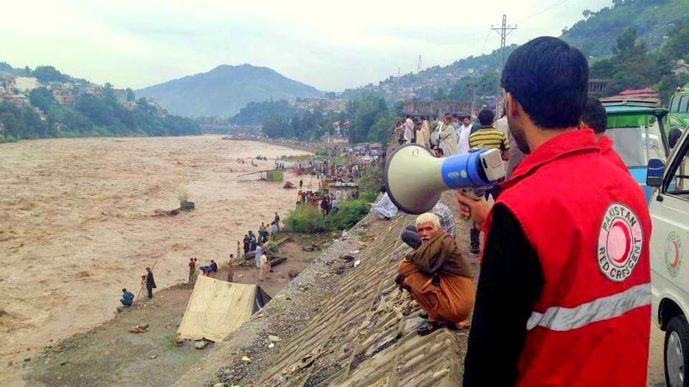 A response team member of the Pakistan Red Crescent Society issues an alert on a mega phone to people near the junction of Jhelum and Neelum rivers in Muzaffarabad district.