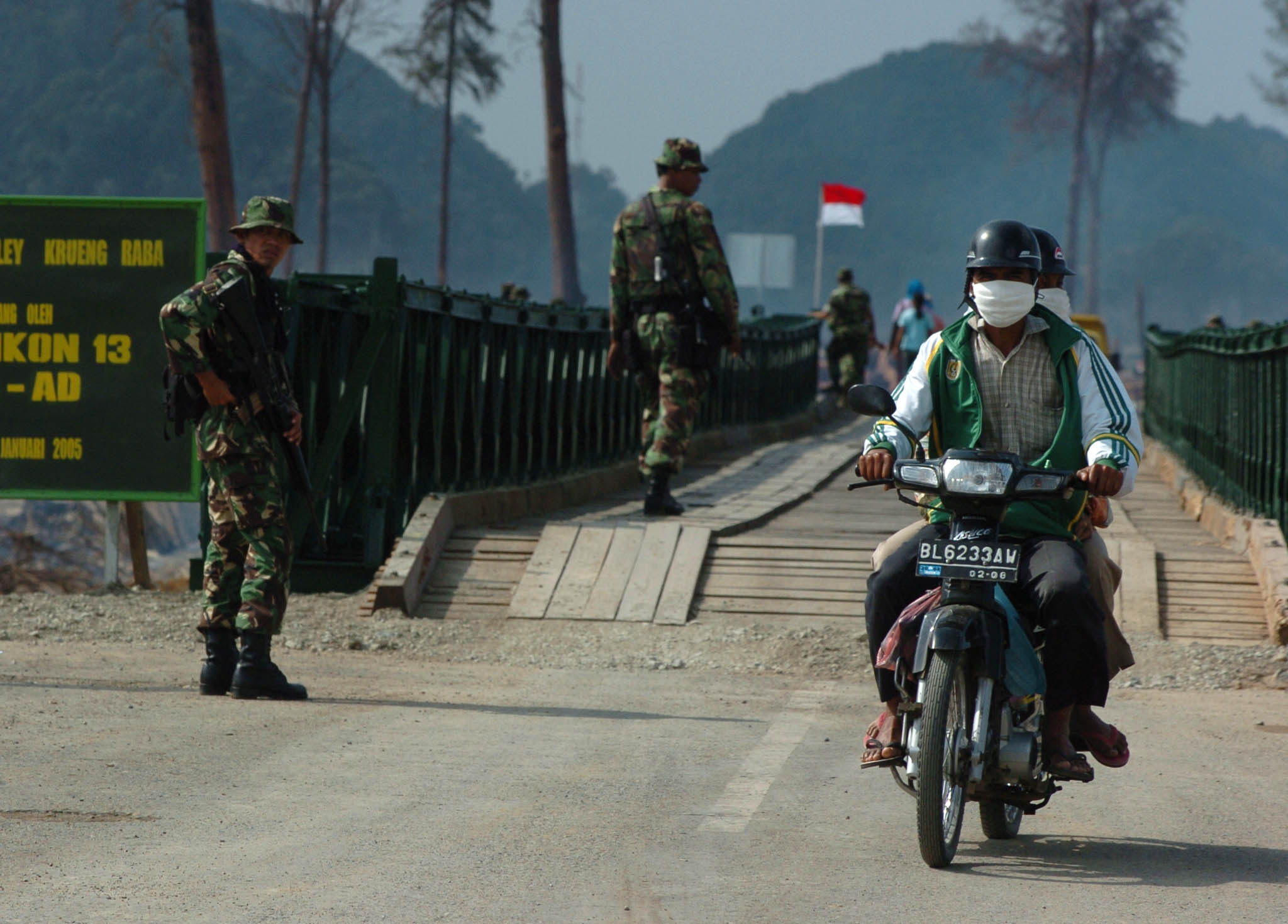 Un habitant d’Aceh traverse à moto un pont surveillé par l’armée à Krueng Raba, Aceh Besar (photo d’archives 2004) An Acehnese resident rides on a bridge guarded by the army in Krueng Raba, Aceh Besar (File photo 2004)