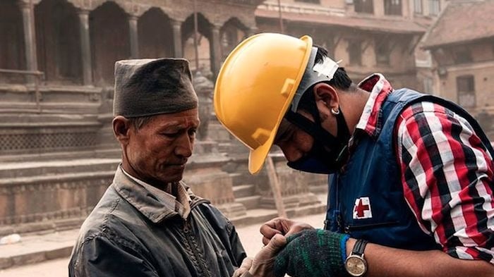 A Red Cross worker tends to an injured Nepali man after an earthquake on Saturday