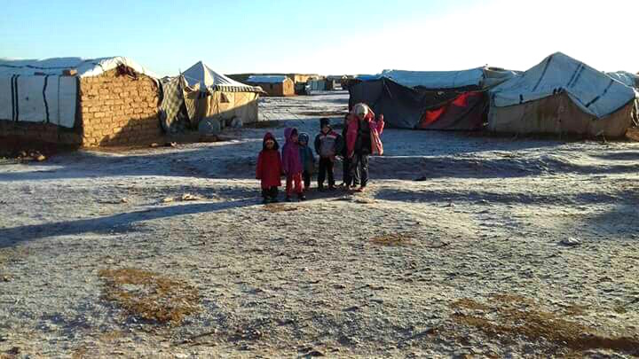 A family poses after snow for a mobile phone photo at the Jordan-Syria berm zone at the border