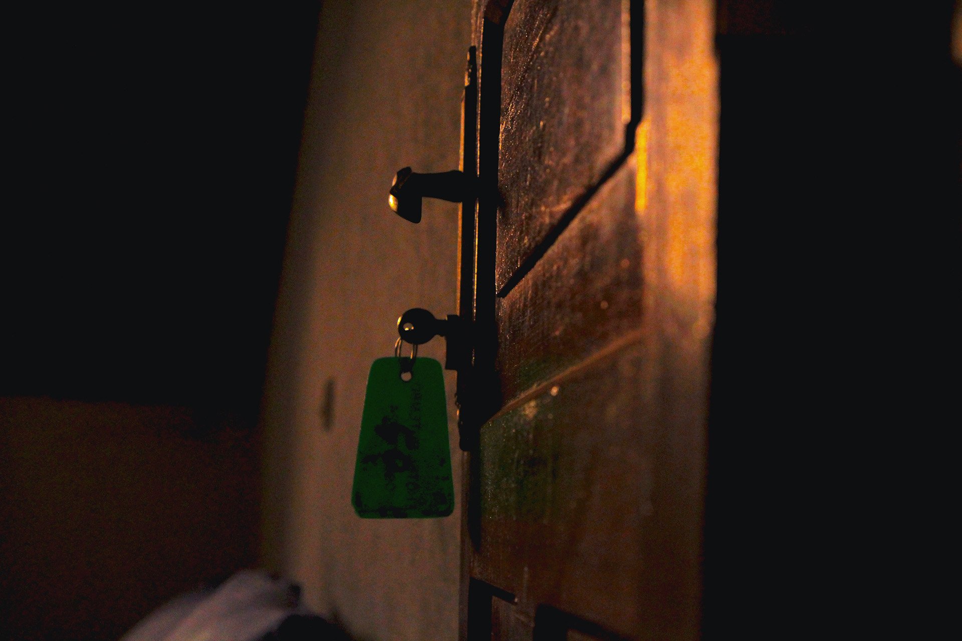 An image of a door with a hotel key in the lock, lit in dim interior lighting.