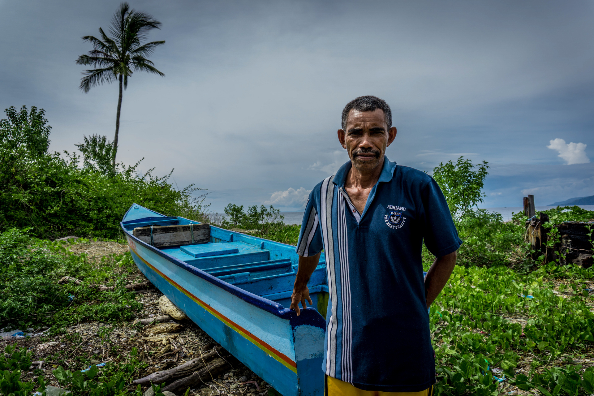 A fisherman in front of a boat and the sea