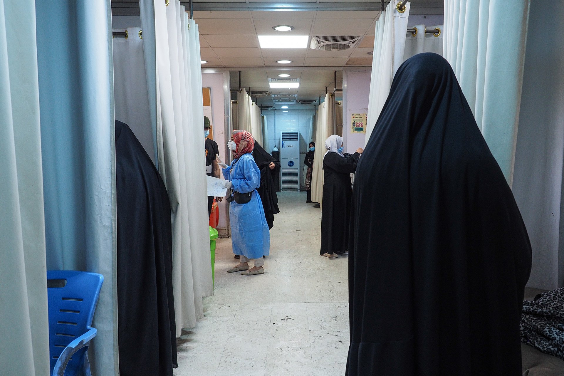 Several people stand in a hospital room. 