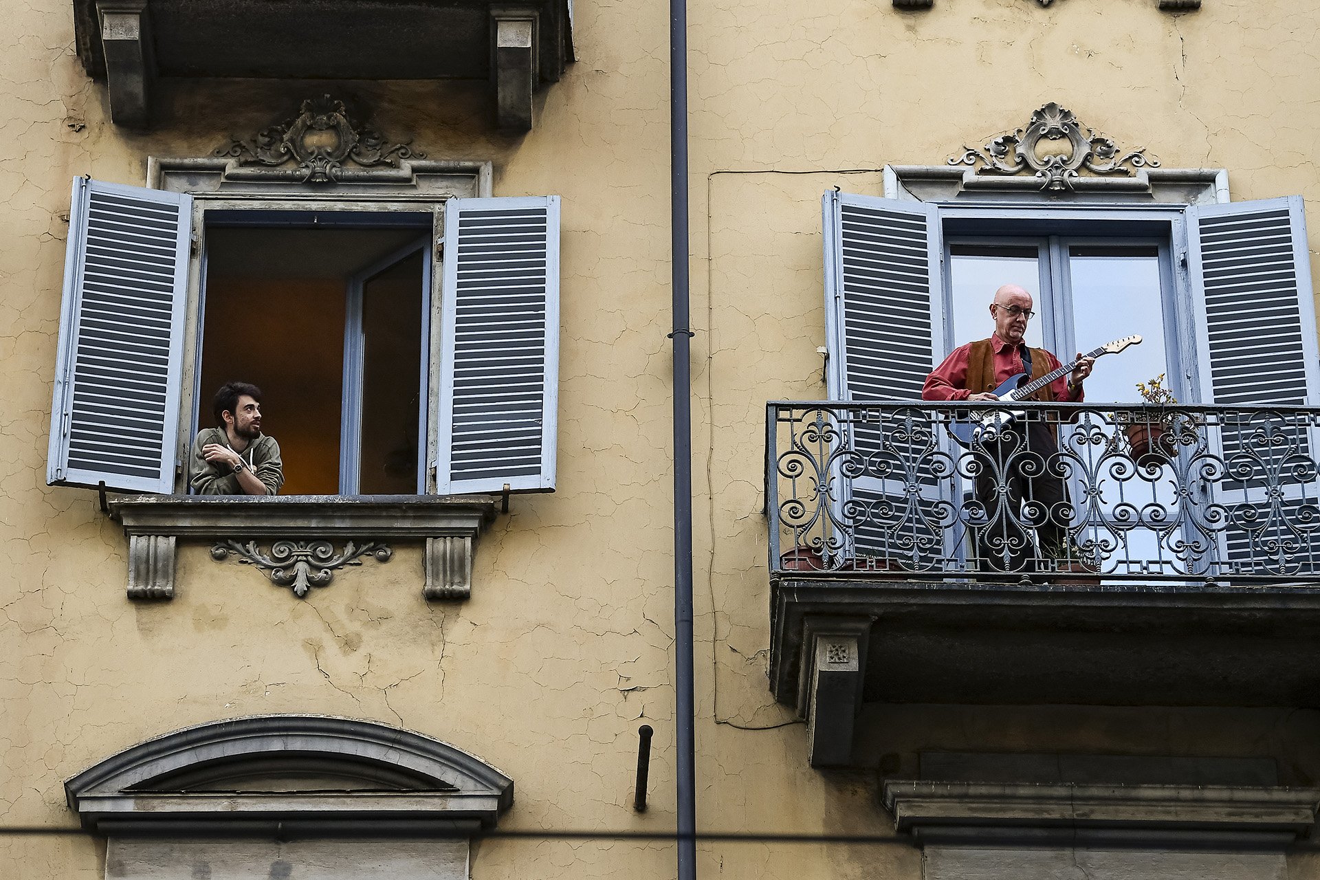 A man plays guitar from his balcony in Turin, Italy