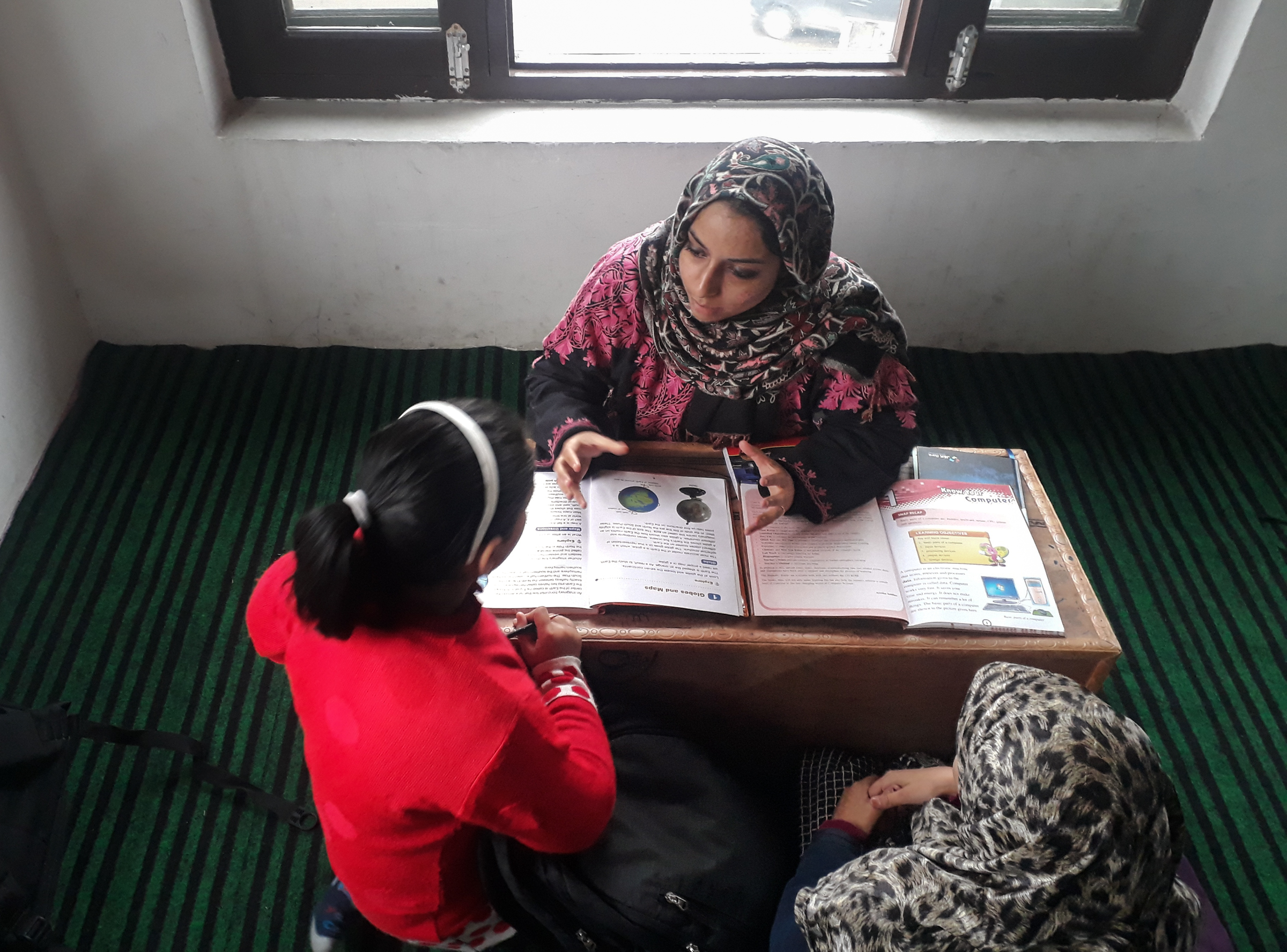 A volunteer tutor teaches students at a pop-up community school in Srinagar. These makeshift classes have become a common sight when violence disrupts education in Kashmir.