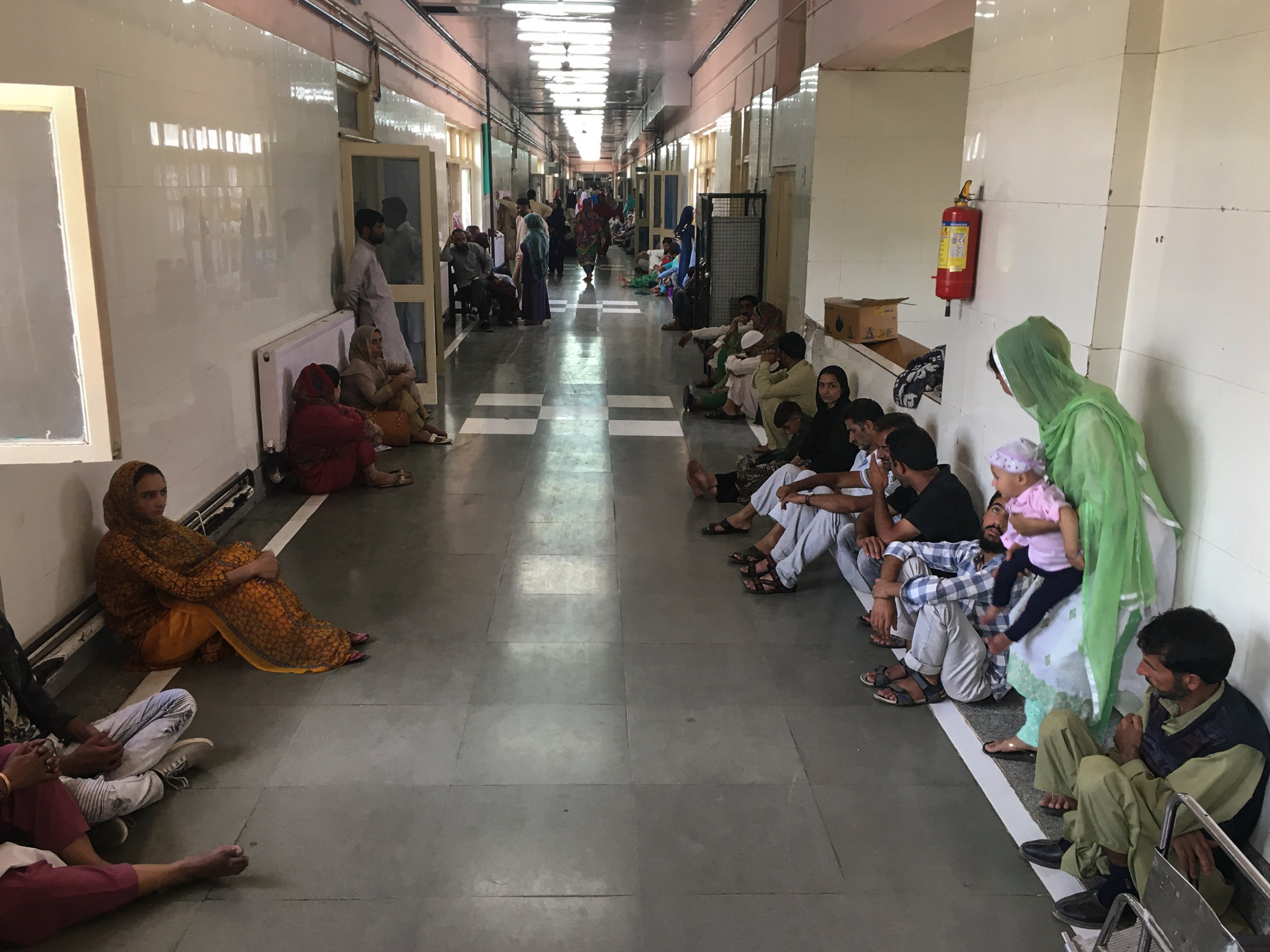 Photo of people sitting in the hallways of a hospital in Srinagar, Kashmir.