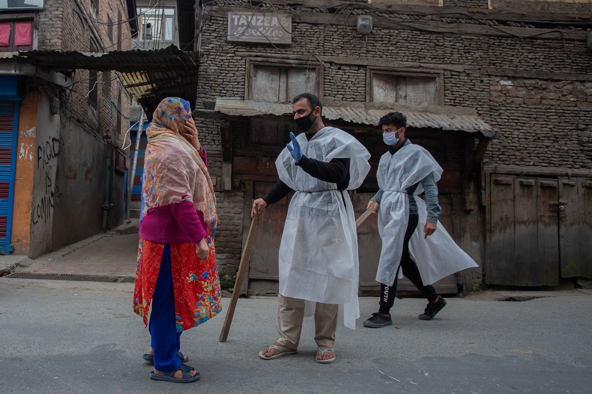 Volunteers stop a woman during lockdowns in a Srinagar neighbourhood