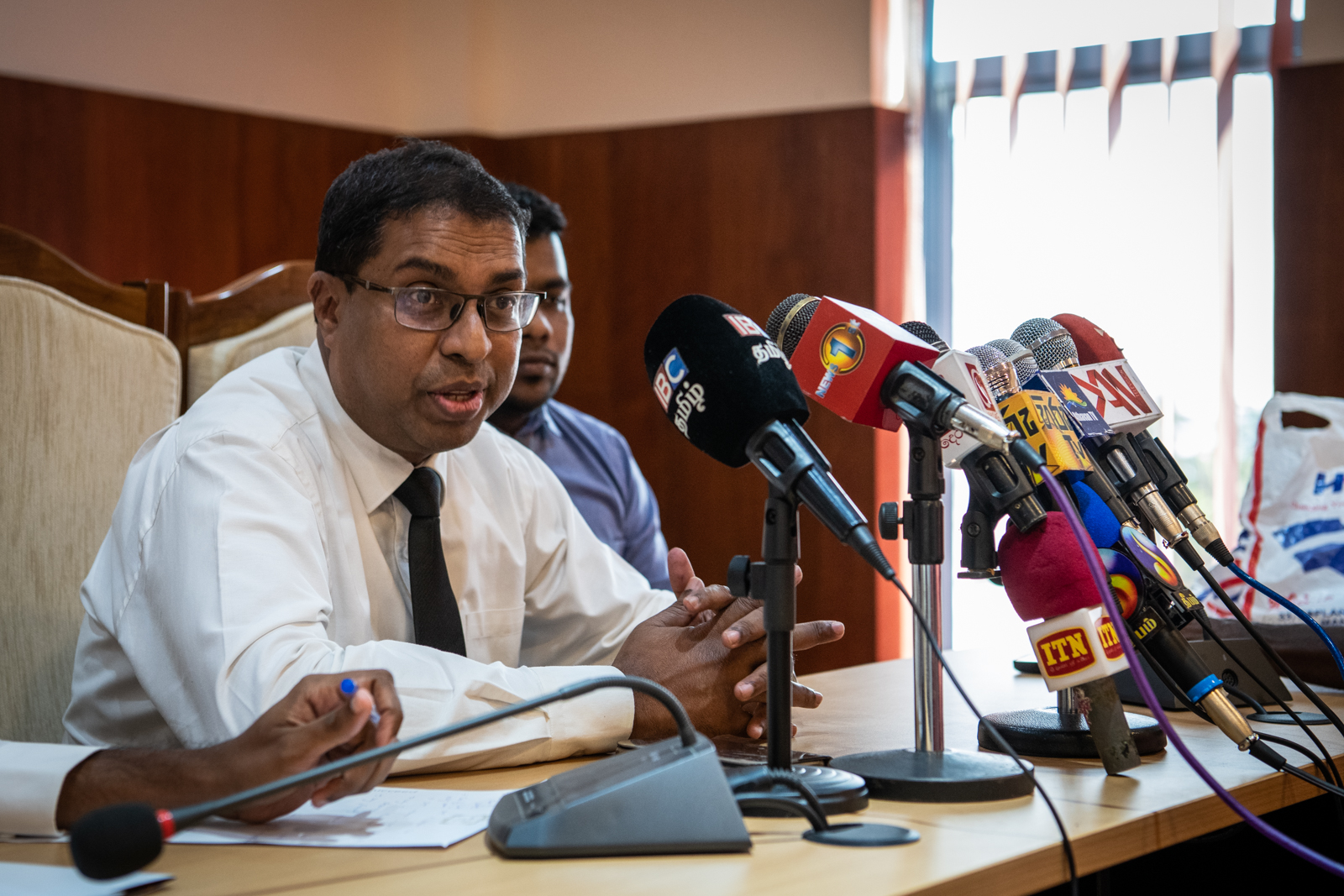 A man sits in front of microphones at a press conference