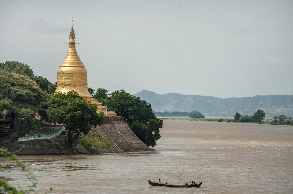 A riverside scene with a boat and a golden pagoda.