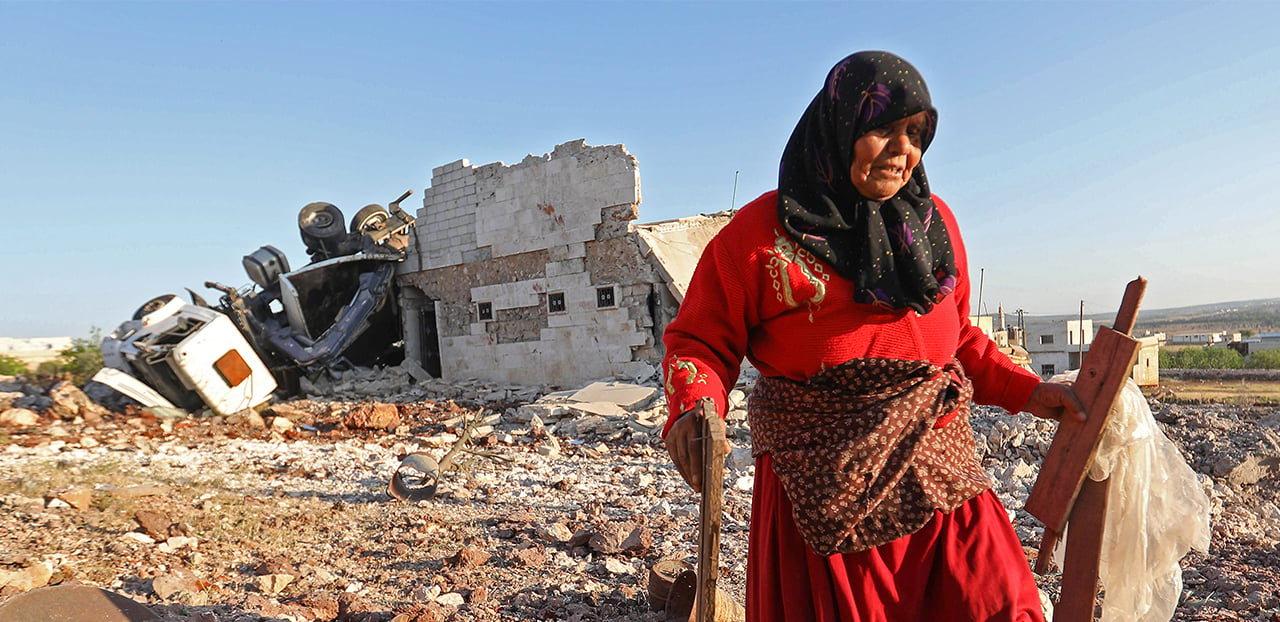 Photo of woman in Idlib near a destroyed building after air strike