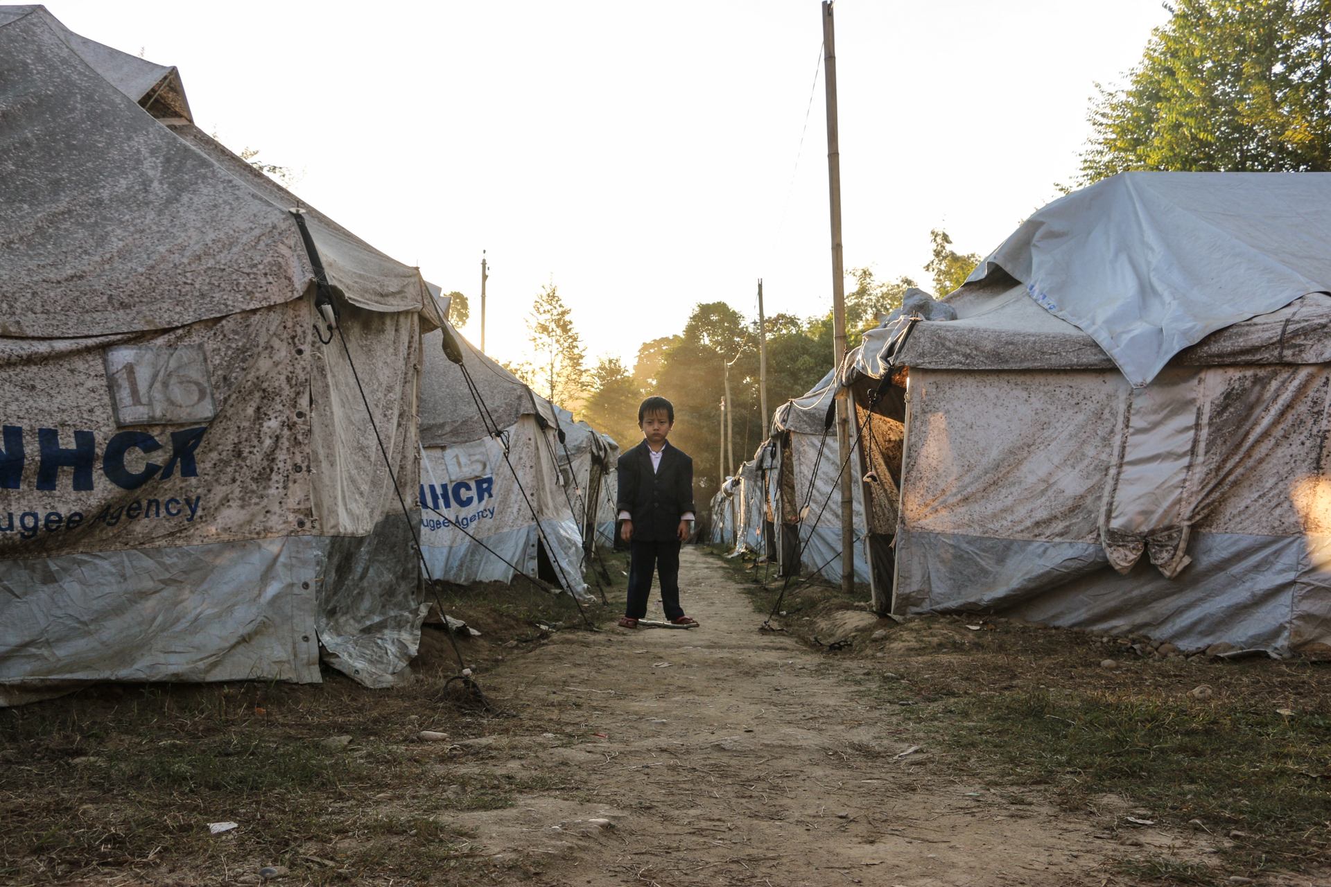 A boy stands in the middle of a displacement camp on a church compound near Myitkyina