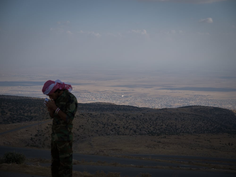 Kurdish fighter has a cigarette as battle for Sinjar city rages below