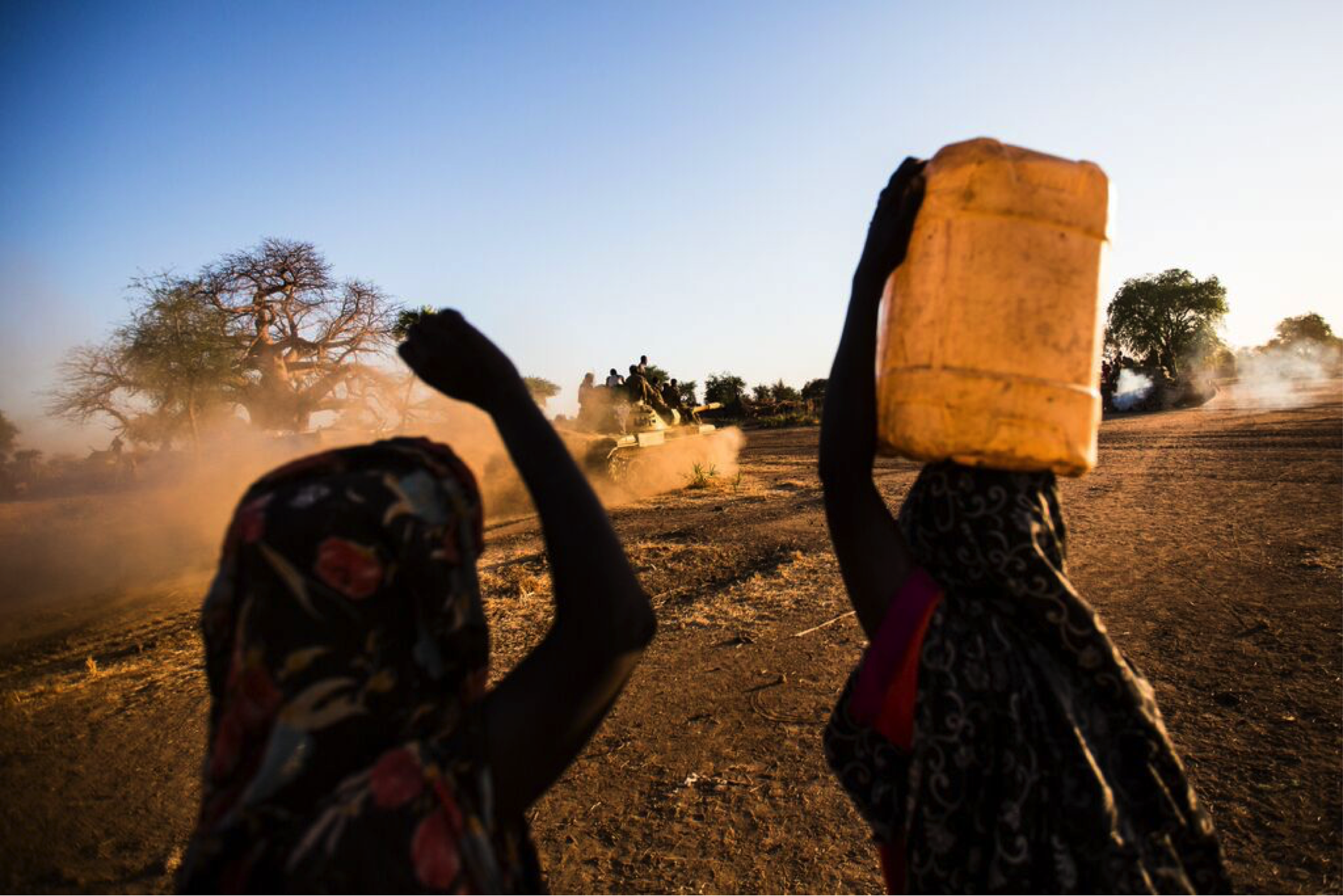 two women walk carrying water