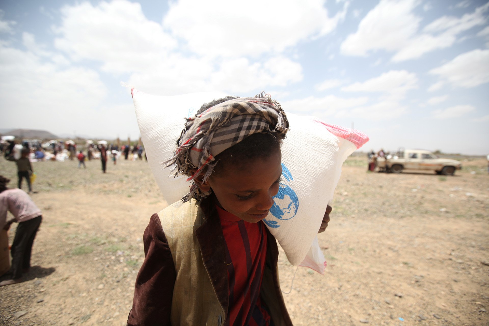 A boy carries food aid he received from the local charity, Mona Relief, on the outskirts of Sanaa, Yemen.