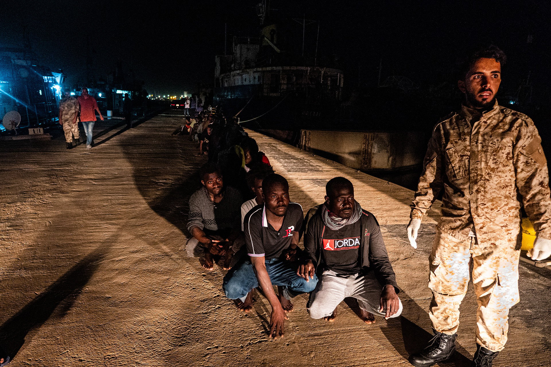 Migrants wait in line at Tripoli’s naval base