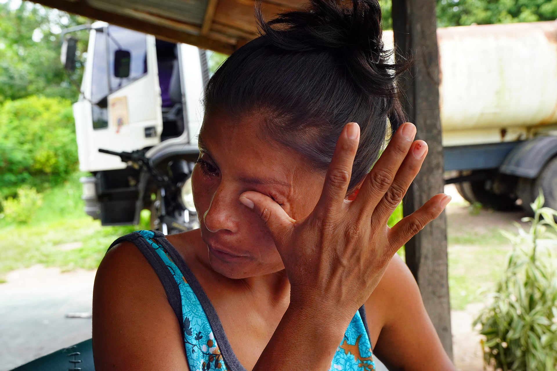 A grieving woman wipes a tear from her eyes