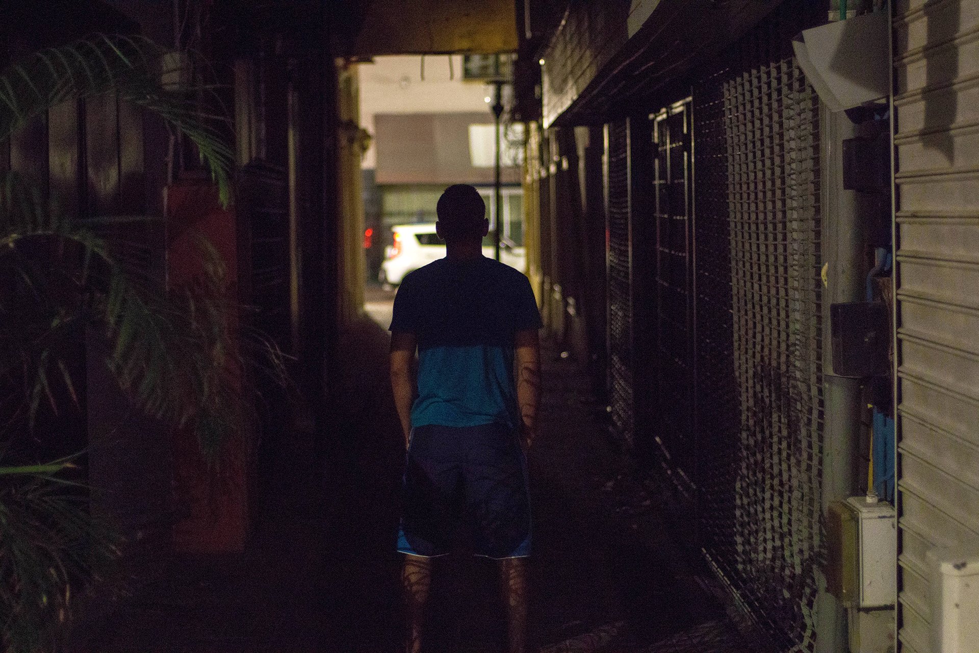 A silhouette of a man facing away in a dark alley.