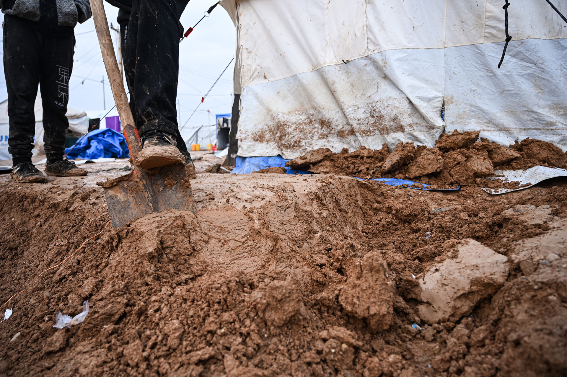 An image of young men piling dirt on the edges of their newly-constructed tent