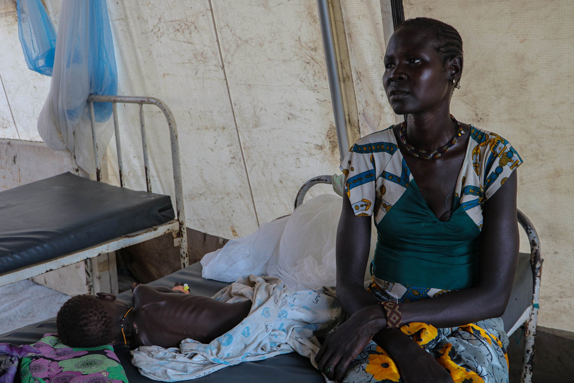 A mother sits with her malnourished child on a bed in Pibor’s main health centre.