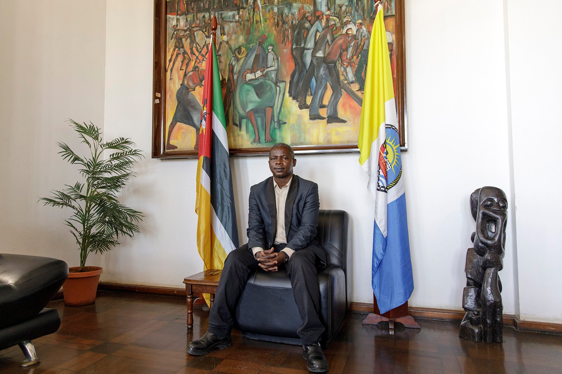 A man sits in a chair in an office beneath a display of different flags.