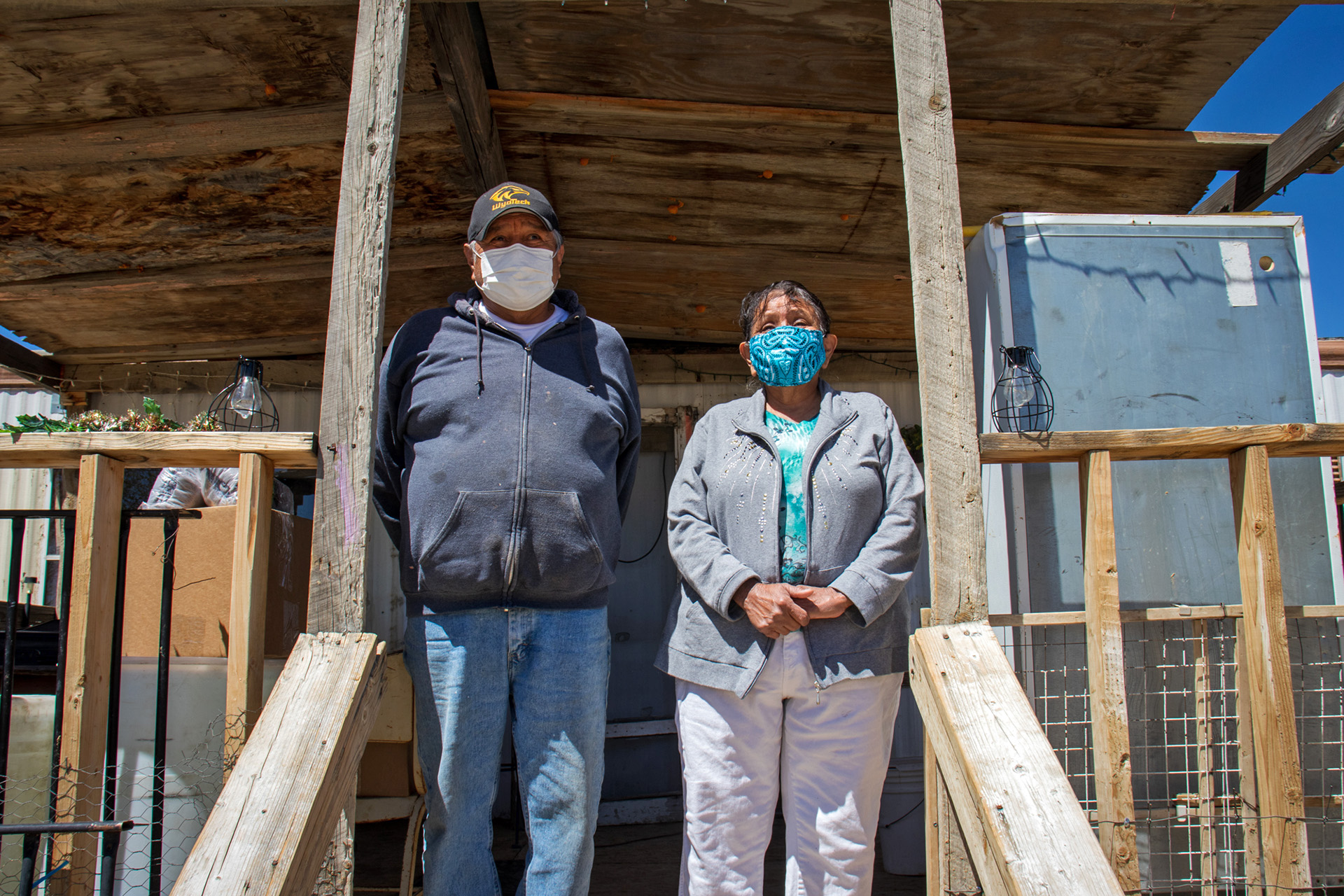 Harry Tsosie and his wife, Grace, stand on their front porch in Pueblo Pintado on the Navajo Nation in April 2021. Tribal employees have delivered essential goods and health checks to the couple since the pandemic began.