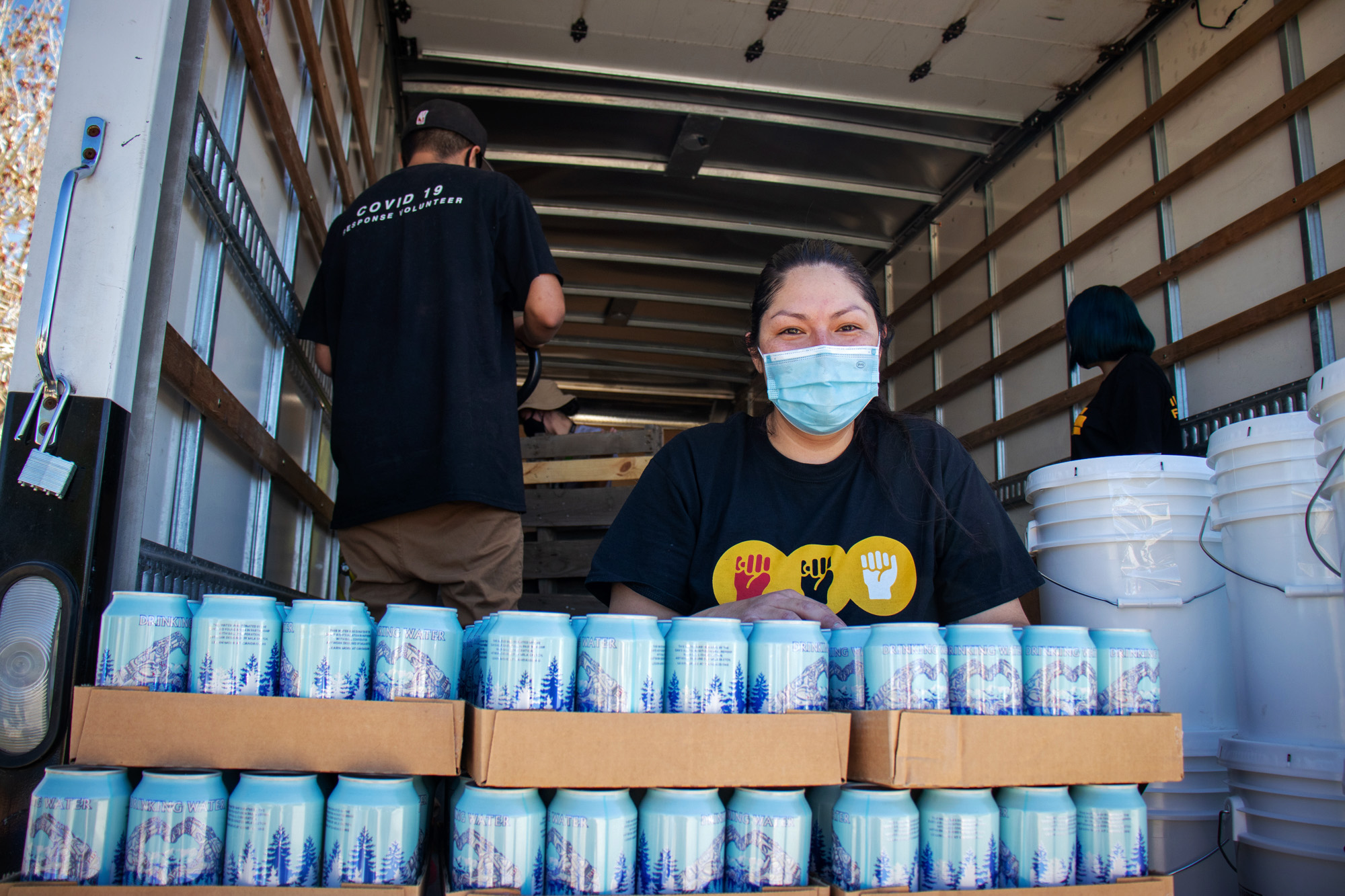 Krystal Curley, executive director of tIndigenous Lifeways, unloads cans of water for distribution. Her non-profit delivers essentials to parts of the reservation where water and electricity are scarce.