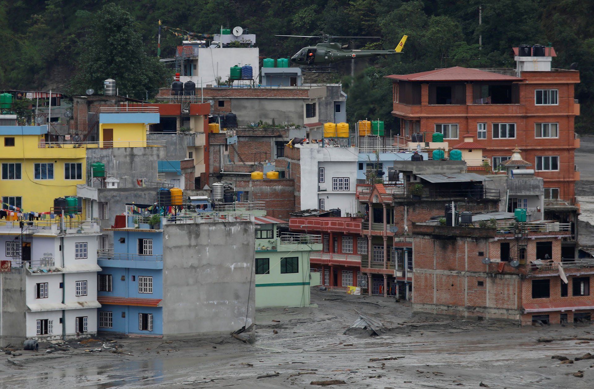 A Nepali army helicopter hovers above houses during a rescue mission as floodwater from the swollen Melamchi river enters the village in Sindhupalchok, Nepal, in June 2021.